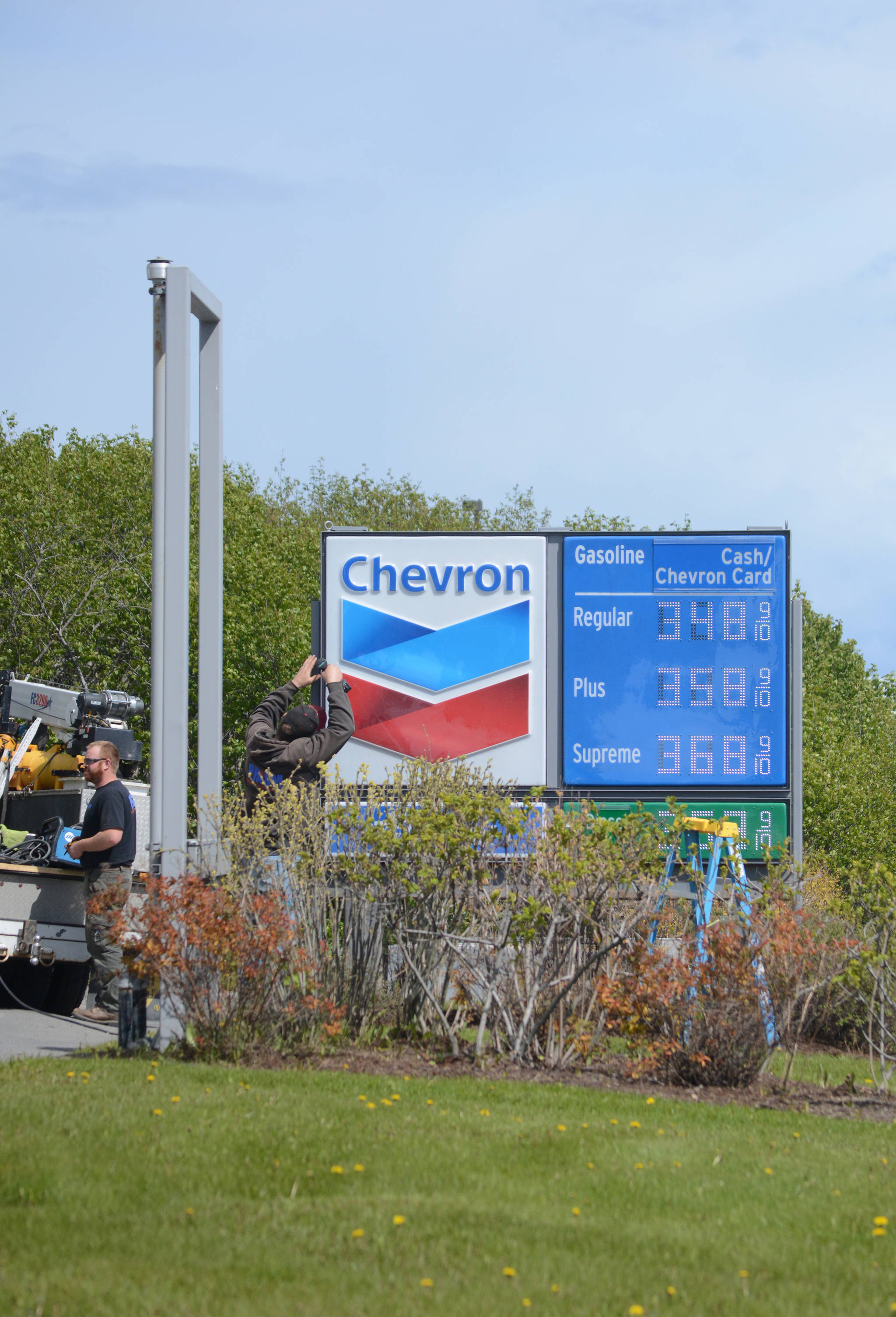 A worker with Prism Design and Construction, Wasilla, on Thursday, May 31, installs Chevron signs at the Essential One gas station on the Sterling Highway and Poopdeck Street. (Photo by Michael Armstrong/Homer News)