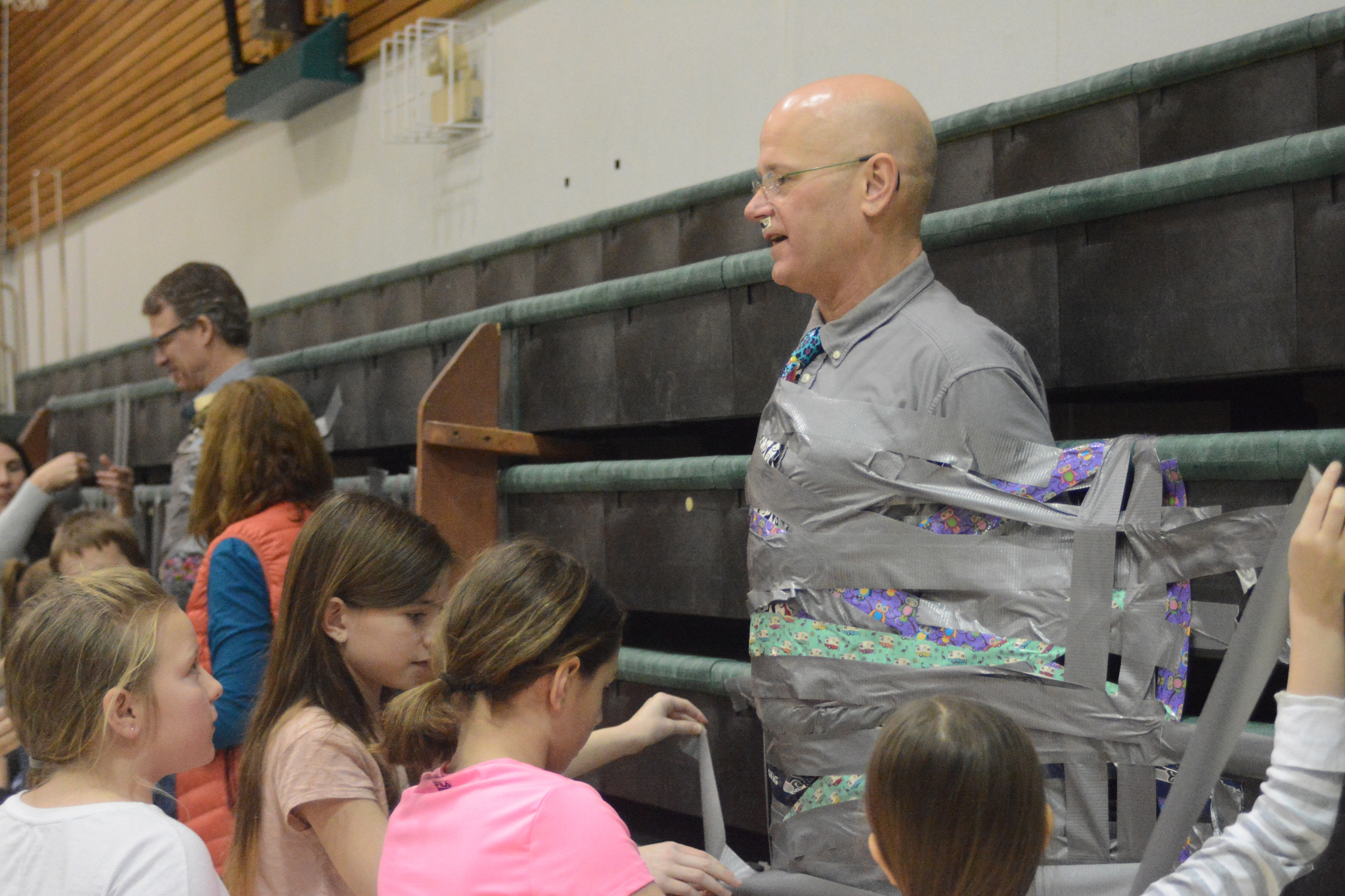 Students at West Homer Elementary School and Fireweed Academy duct tape their principals to the wall in the mutlipurpose room. At left is West Homer Elementary Principal Eric Waltenbaugh and at right is Fireweed Academy Principal Todd Hindman. The students got the reward of plastering duct tape across the principals for filling up a jar with tokens handed out when a student showed good behavior like being respectful and responsible.
