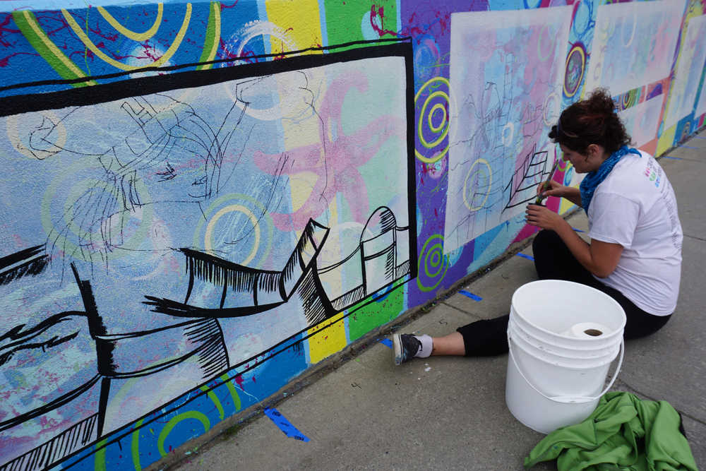 Kady Perry works on the Heath Street mural last Friday.  David Brame wrote the story told in the series of panels.