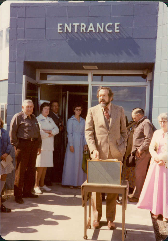 Hospital staff and local and state officials gather to celebrate the grand opening of the South Peninsula Hospital's new location on Bartlett Street in 1977. Helen Alm, a nurse who worked in the hospital's first location, starting in the 1950s, looks on from the entrance in a white nurse's uniform. The new hospital opened on July 1 with 17 beds and is at the same location that the hospital is located today.