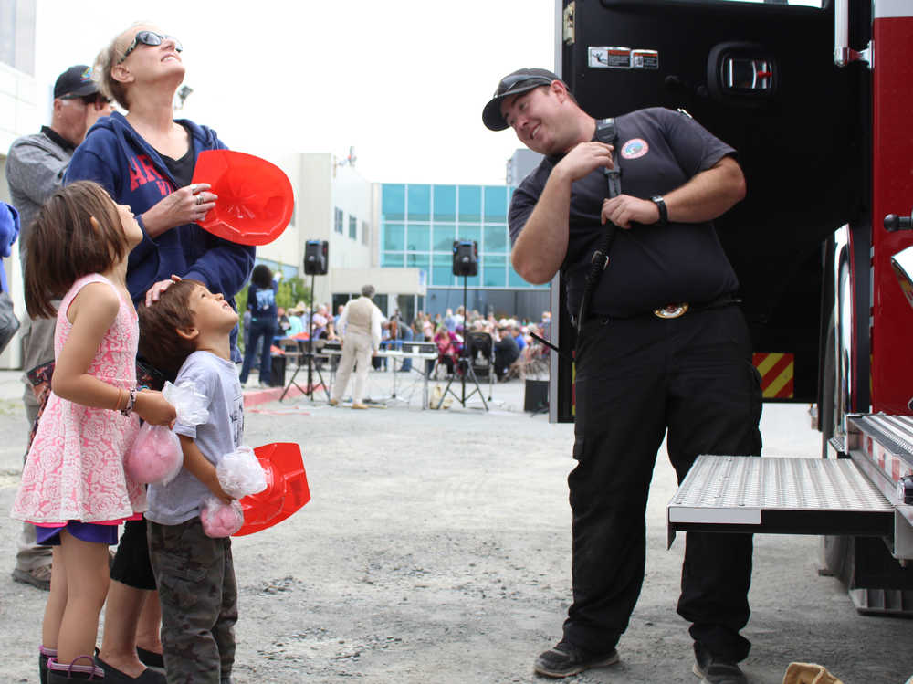 Taylor Wilson of Kachemak Emergency Services tells Jerilyn Wright and her grandchildren Ahnali and Nakoa Cook about the features of the fire truck present at the South Peninsula Hospital 60th Anniversary Party.