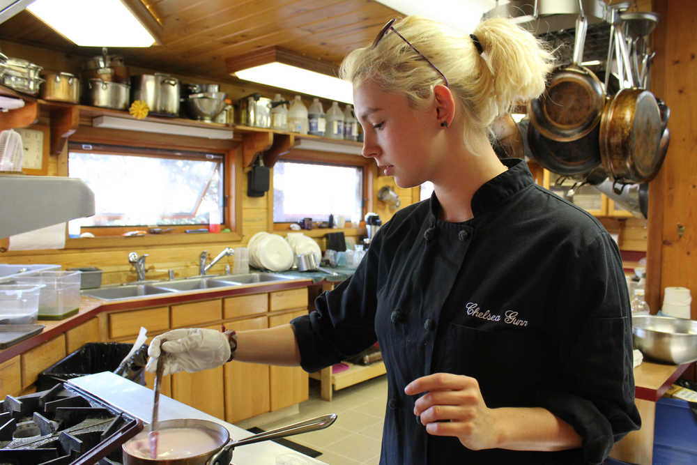 Chelsea Gunn, a cooking instructor at Tutka Bay Lodge, stirs a rose panna cotta mixture on the stove. Gunn will serve the dessert to the guests at her afternoon cooking class.-Photo by Anna Frost, Homer News