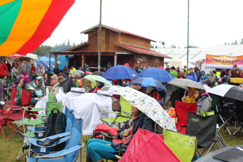 Festival guests sit under umbrellas and use tarps to keep dry while enjoying the music at Salmonfest on a rainy Saturday, August 6.