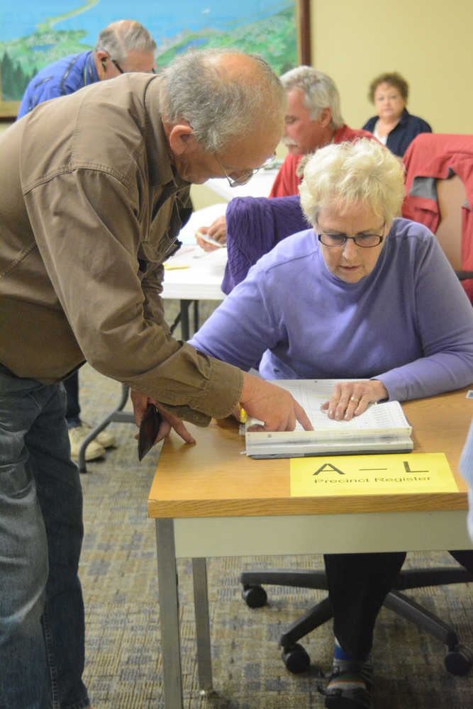Steve Gibson, left, points to his name on the voter rolls at Homer City Hall to poll worker Mariann Lyda.