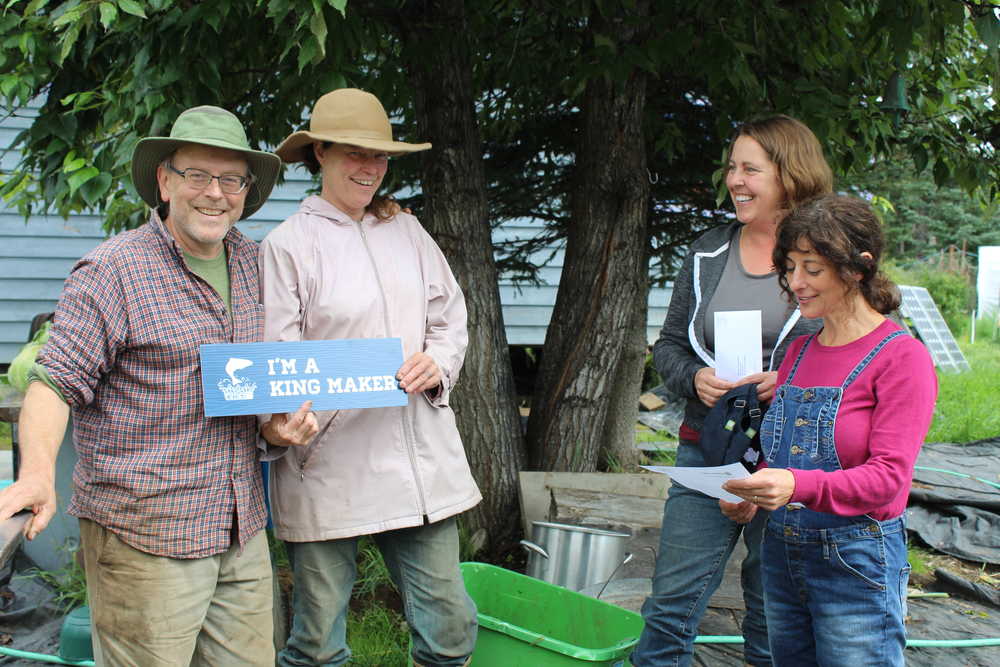 Paul and Jen Castellani smile as Denise Jantz of Kachemak Heritage Land Trust and Coowe Walker of Kachemak Bay Research Reserve present them with the King Maker award for their care for their land, which has a stream with baby salmon in it. Walker reads a letter from KHLT explaining why the Castellanis are deserving of the King Maker award.