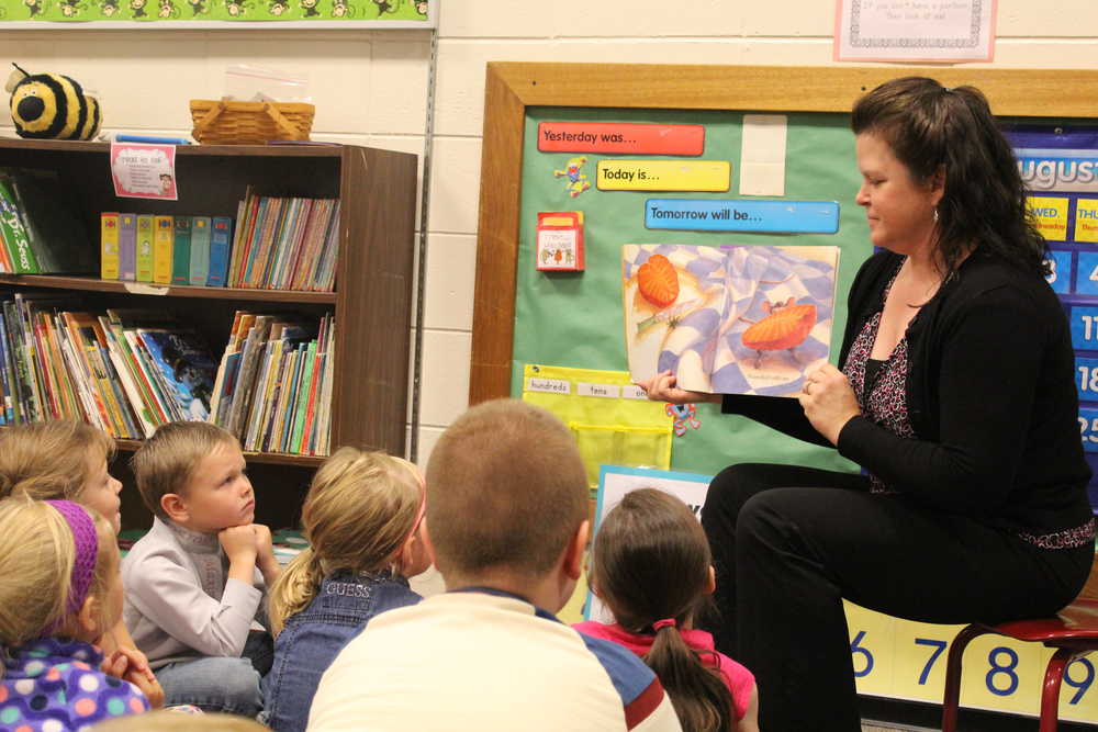 8:19 a.m.: Anne Love reads The Little Mouse, the Red Ripe Strawberry, and the Big Hungry Bear to her first grade class. Love gathered the kids on a rug with circles on it for each child to sit on and went over "Rug Rules," which include eye contact with teacher, listening, sitting cross-legged, hands in lap, and raises one's hand for permission to speak. She also told them that the class would keep count of the books they read as a class - 100 books earns a popcorn party and 200 books earns a pizza party.