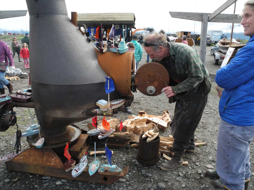 John Miles feeds the wood stove at the Kachemak Bay Wooden Boat Festival last Saturday. Miles volunteers every year to help build the blanks for children to make their own wooden boats.