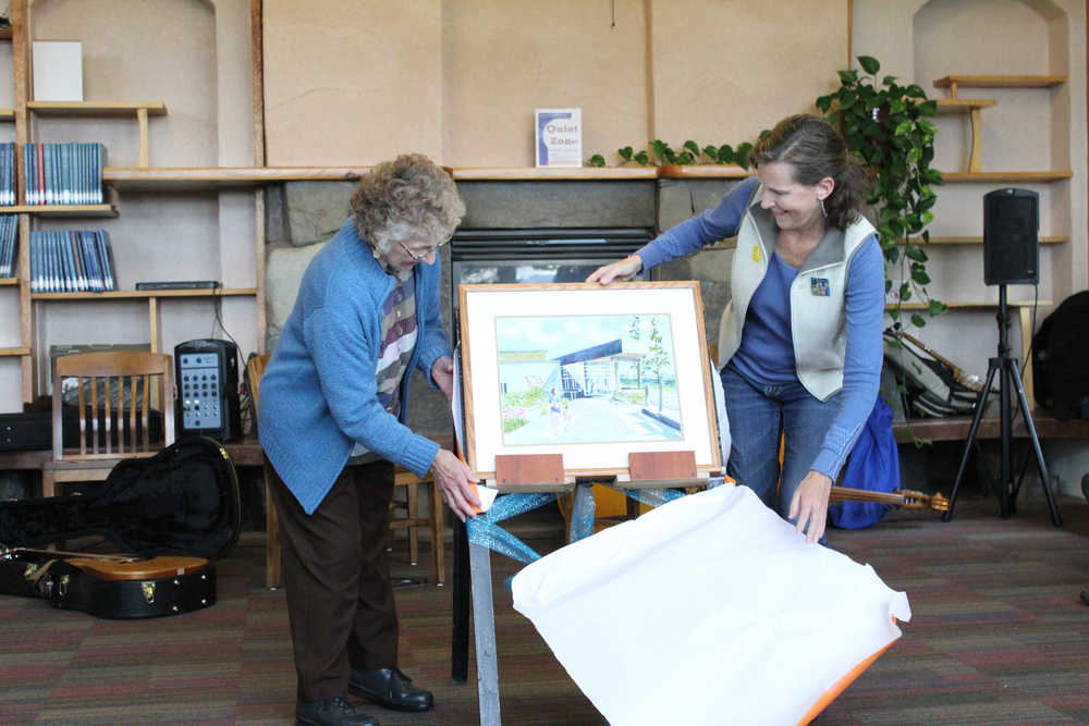 Cleo Webb and Sue Mauger unwrap the new watercolor painting of the Homer Public Library building, painted by local artist Jan Peyton, at the library building's 10th birthday celebration on Saturday, Sept. 17.