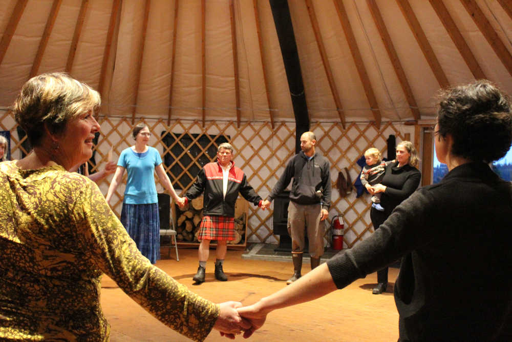 Pegge Paver looks toward her neighbor as a group prepares to contra dance in a yurt at Ageya Wilderness Center as part of the Homer Folk School grand opening event on Saturday, Oct. 8.