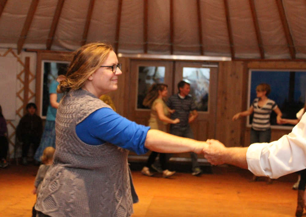 Robin McAllistar, board member of the Homer Folk School, takes a neighbors hand during contra dance at the folk school's grand opening event on Saturday, Oct. 8.