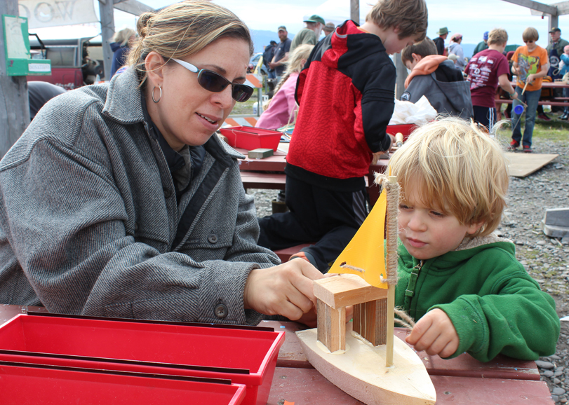 Left, mother and son boat-building team Amy and Elias Sundheim put finishing touches on a sailboat at the festival on Sunday.-Photo by McKibben Jackinsky,  Homer News