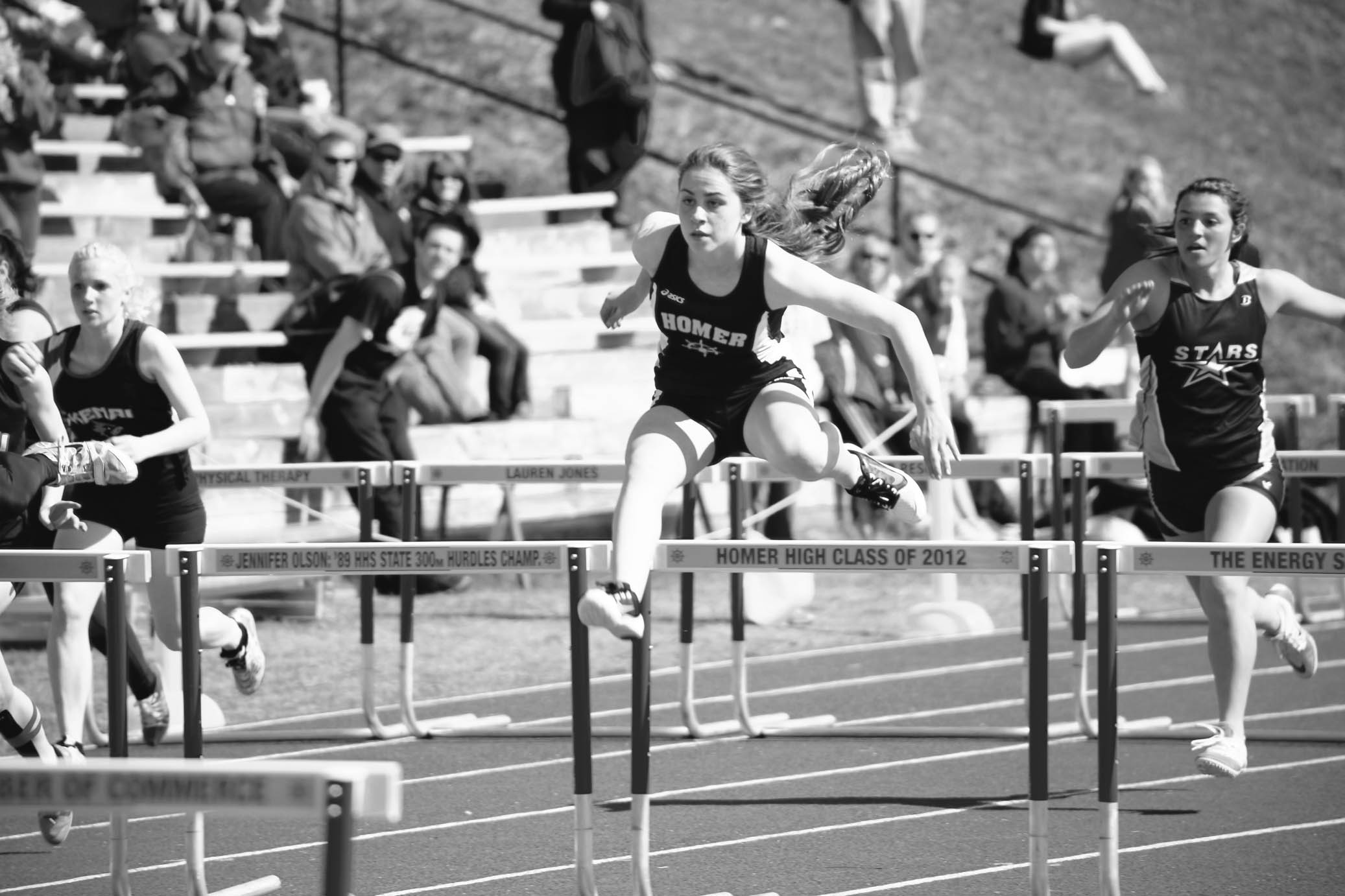 Lauren Evarts, center, leaps over the hurdles in the 100-meter event. She took first place.-Photo by Aaron Carpenter, Homer News