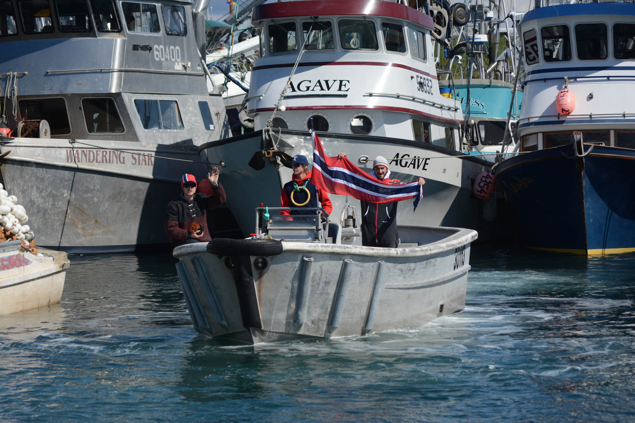 Fishermen wave Norwegian banners as King Harald V passes by on the Rainbow Connection in the Homer Harbor.-Photo by Michael Armstrong; Homer News