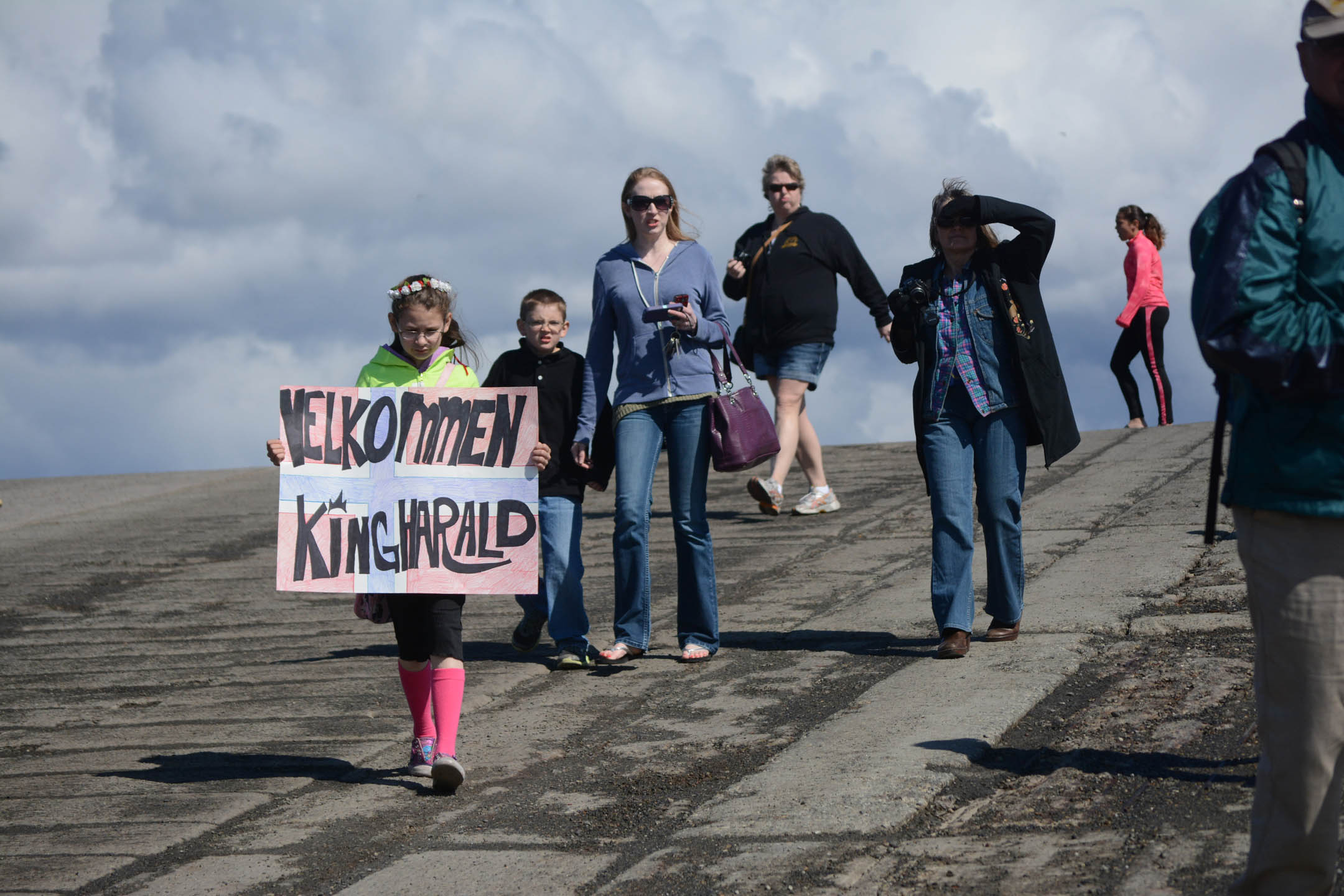 Carly Johnson carries a sign that reads "Welcome, King Harald," at the Homer Harbor on Tuesday morning.-Photo by Michael Armstrong; Homer News