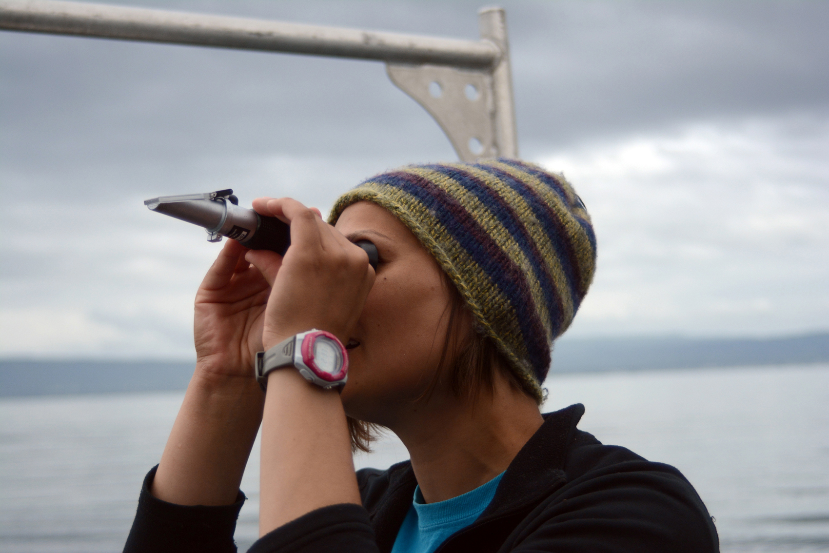 Becca Matthias, a naturalist for the Center for Alaskan Coastal Studies, looks through a refractometer to measure salinity in an ocean water sample taken during a recent tour. The CACS tours, offered on Thursdays, are an opportunity to combine science and sightseeing.-Photo by Michael Armstrong, Homer News