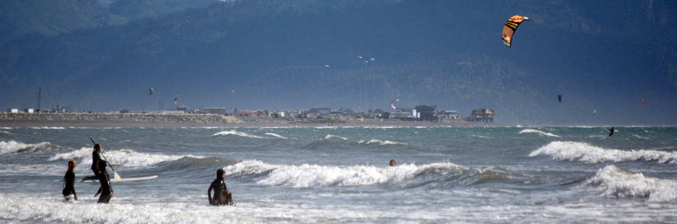 Kite surfers, stand-up paddleboarders and body surfers play in the waves off the Spit last month.-photo by Michael Armstrong, Homer News
