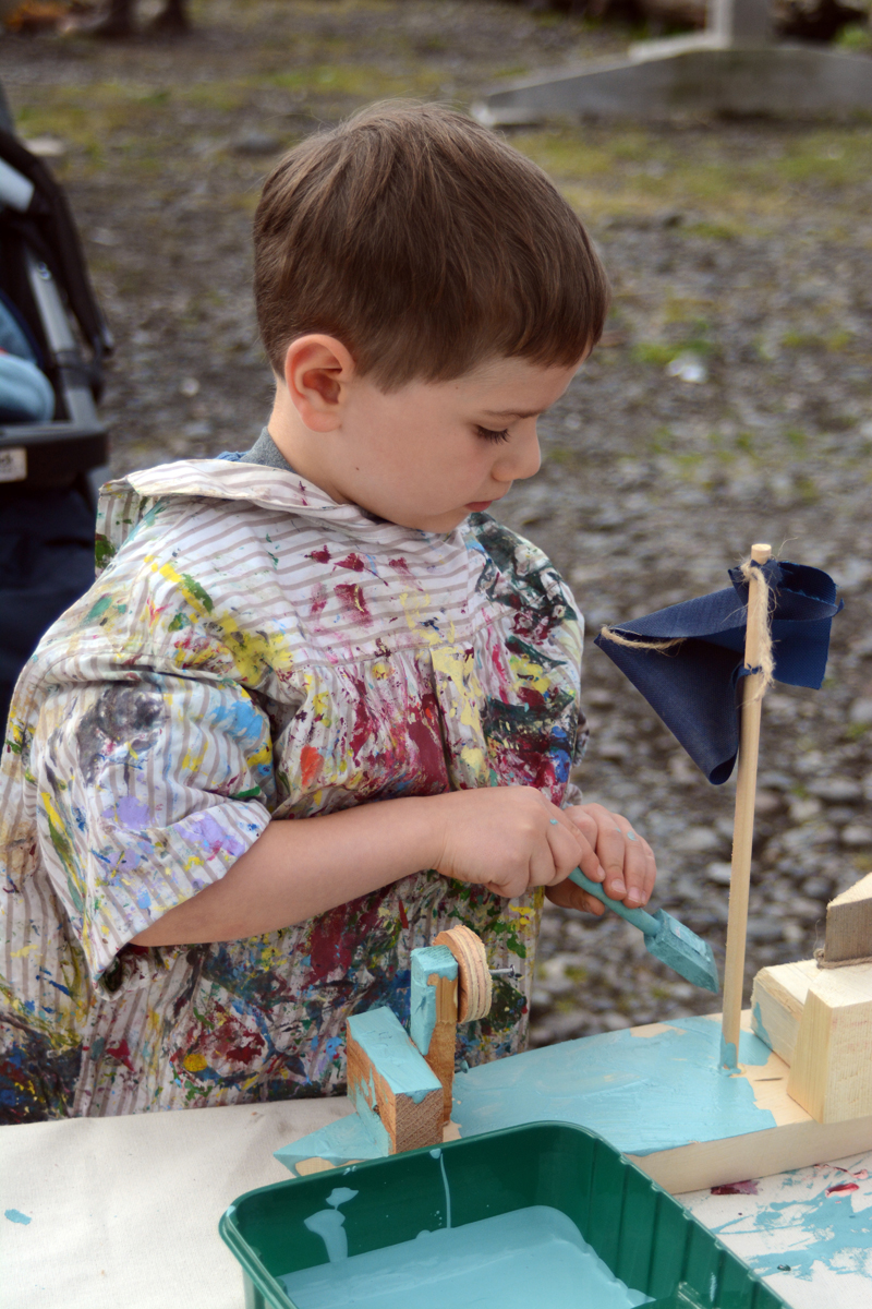 Steven Michael Allen paints his wooden boat at the Kachemak Bay Wooden Boat Festival on Saturday. The boat building shop for kids is always a popular event.-Photo by Michael Armstrong, Homer News