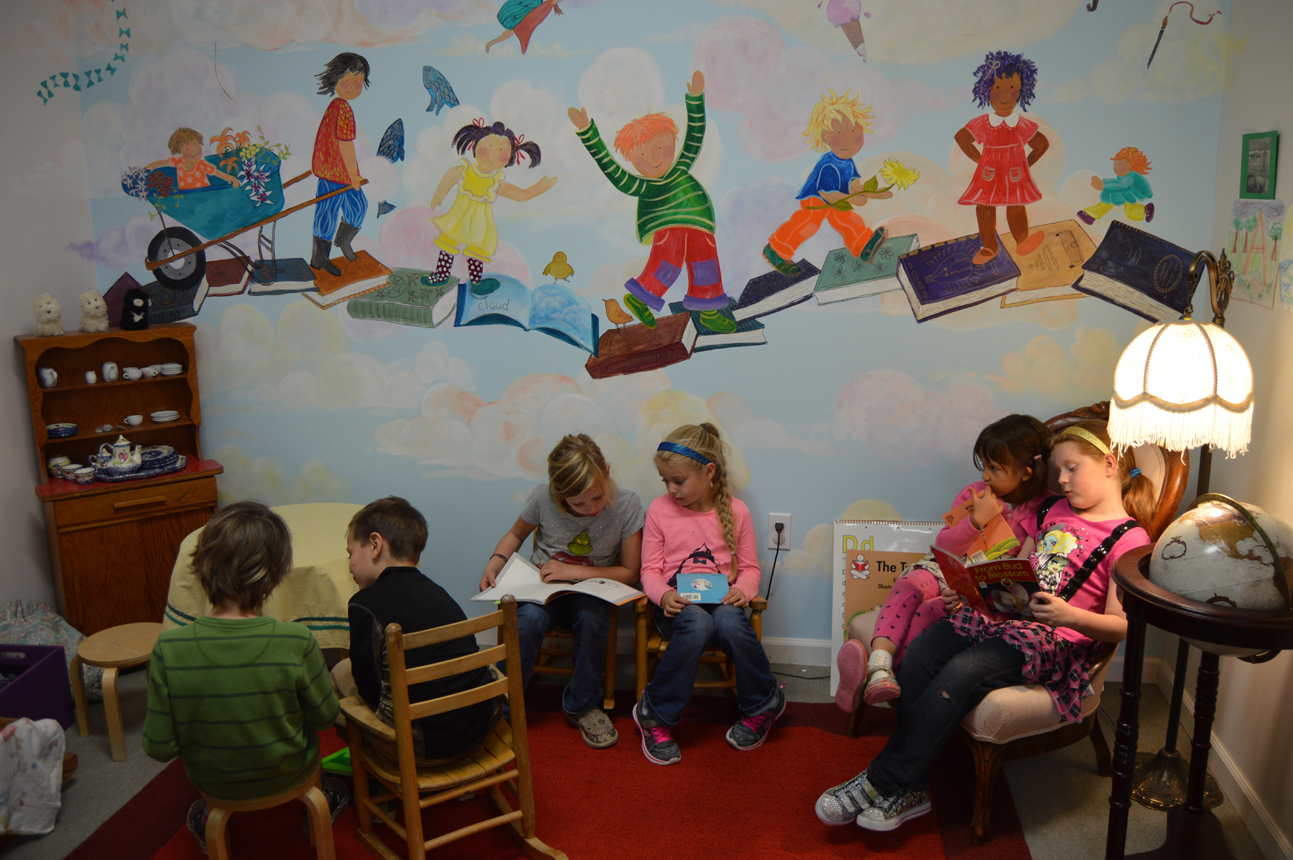 Students at Little Fireweed enjoy Partner Reading Time under a new mural in the library. The mural was completed this summer by local artists.