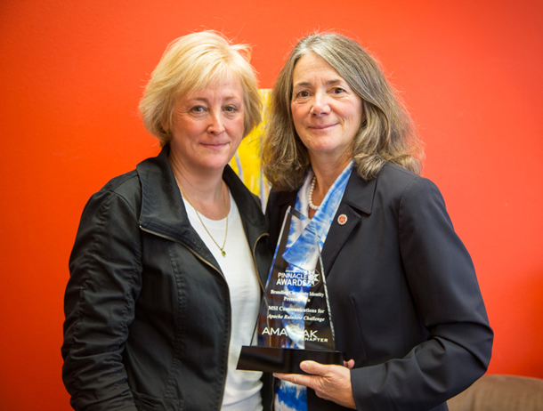 Lisa Parker, right, manager of government relations and external affairs at Apache Corporation, accepts Apache’s Pinnacle Award from Laurie Fagnani, president of MSI Communications, which designed the Apache Rainbow Challenge logo.-Photo provided