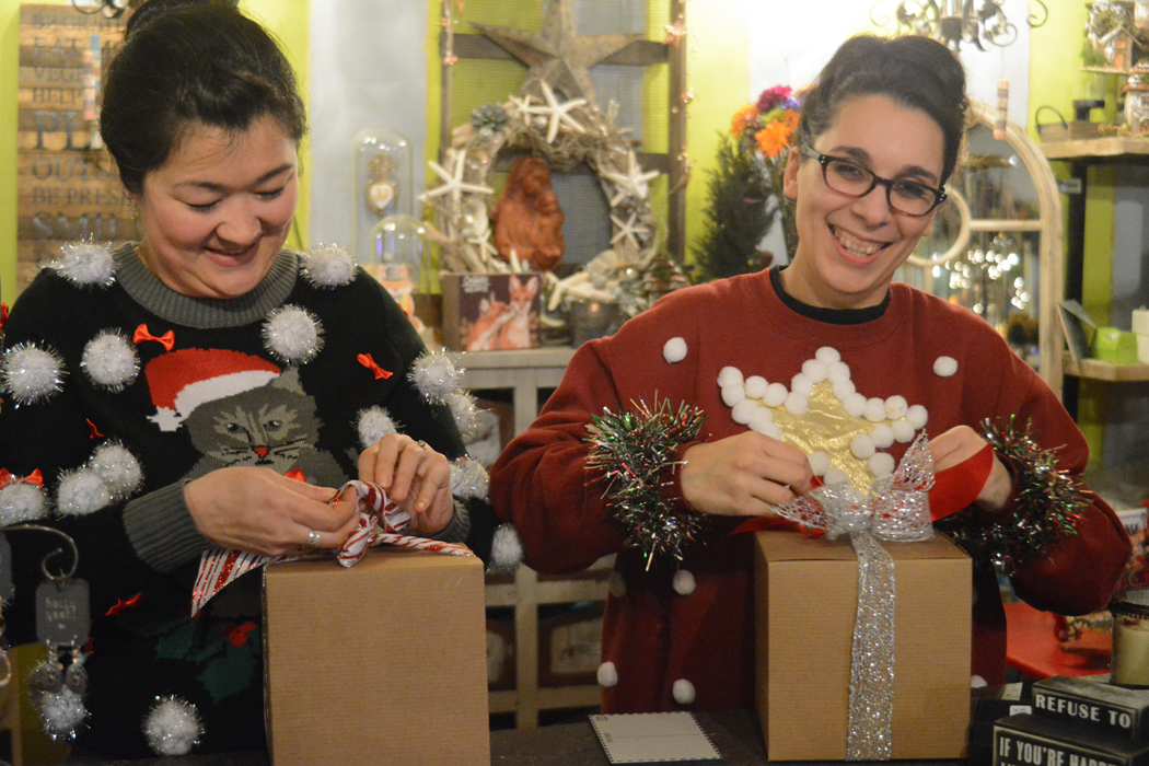 Lindsey Collins, left, and Bekah Dalke, right, wrap presents at Oodalolly last Friday. Dalke, the store’s owner, and Collins wore ugly Christmas sweaters they found at thrift stores.-Photo by Michael Armstrong