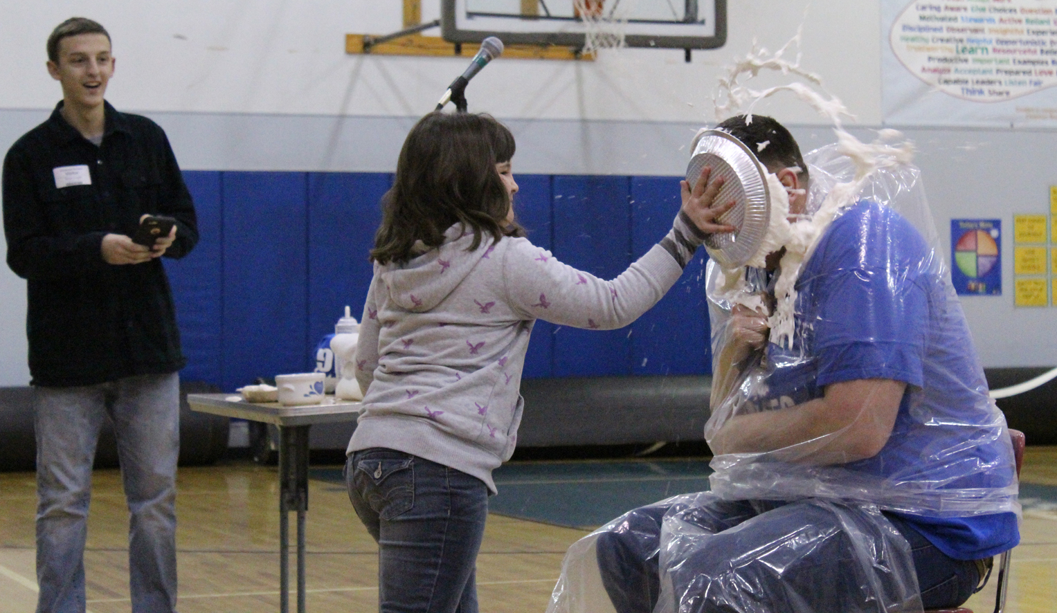 Harley Boon, a Chapman School fourth grader, plants a pie directly in the face of Principal Conrad Woodhead. Harley was drawn as the pie-thrower to represent her class, which raised the most money in the Bethel School fundraiser.-Photo by Anna Frost, Homer News