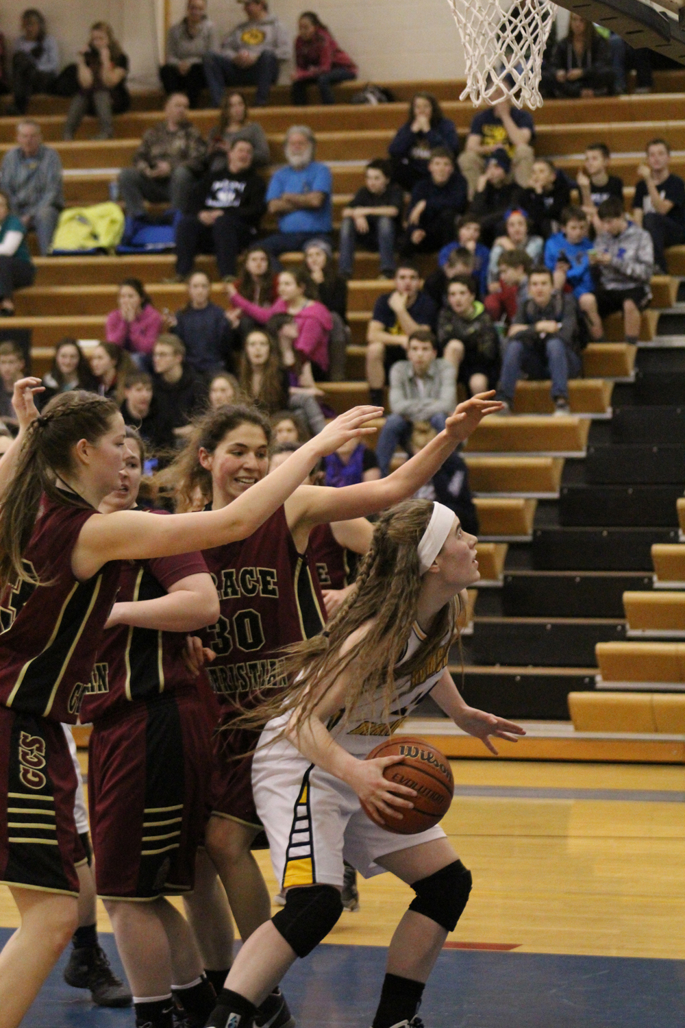 Senior Mariner Madison Akers crouches to block the crowd of grabbing Grace players as she sweeps up the ball to score in the middle of the fourth period. Homer girls varsity won their game against Grace with a final score of 46-35.-Photo by Anna Frost, Homer News
