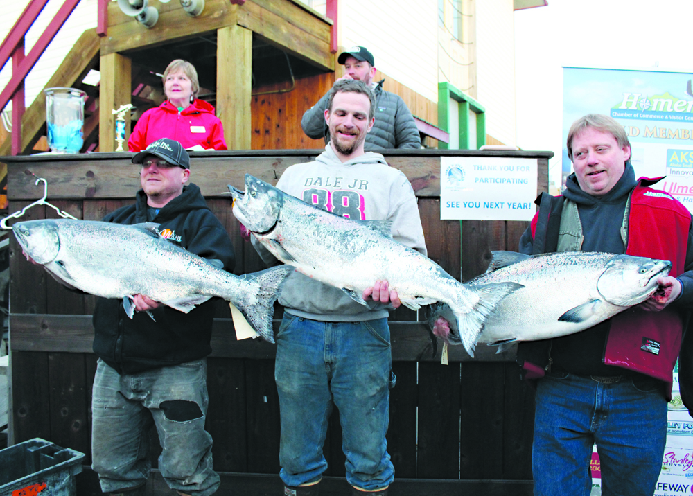 The top three winners in Homer’s 23rd Annual Winter King Salmon Tournament show off their fish to the crowd. From left are Colt Belmonte who placed third with his 24.8-pound king, winning $16,588; Kelly Grose, who placed second and won $21,112 with his 25.25-pound king; and Eric Holland, who took first place with his 26.45-pound king. Holland’s prize of $31,668 was more than the 2015 tournament’s first place prize. All the anglers are Homer residents.-Photo by Anna Frost, Homer News