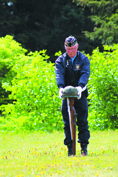 Eric Henley places the helmet on top of the rifle at the Anchor Point Cemetery Memorial Day service on Monday, May 30. The rifle and helmet symbolize the fallen soliders honored in the service.-Photo by Anna Frost, Homer News