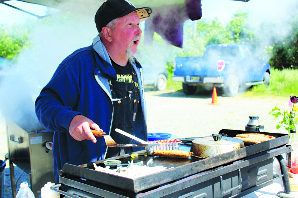 Will Nye looks up to talk to a customer as he cooks sausages with peppers and onions at the McNeil Canyon Meat Company booth at the Market.