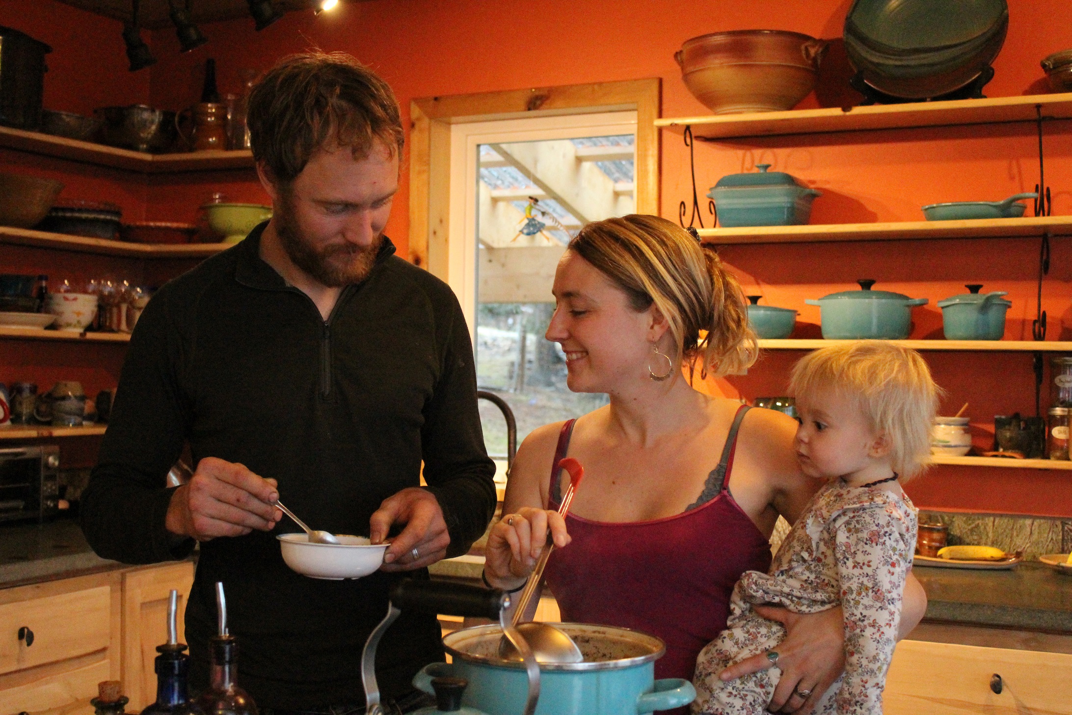 Eivin Kilcher holds a bowl as Eve Kilcher ladles in homemade chicken soup for their daughter Sparrow.-Photo by Anna Frost, Homer News