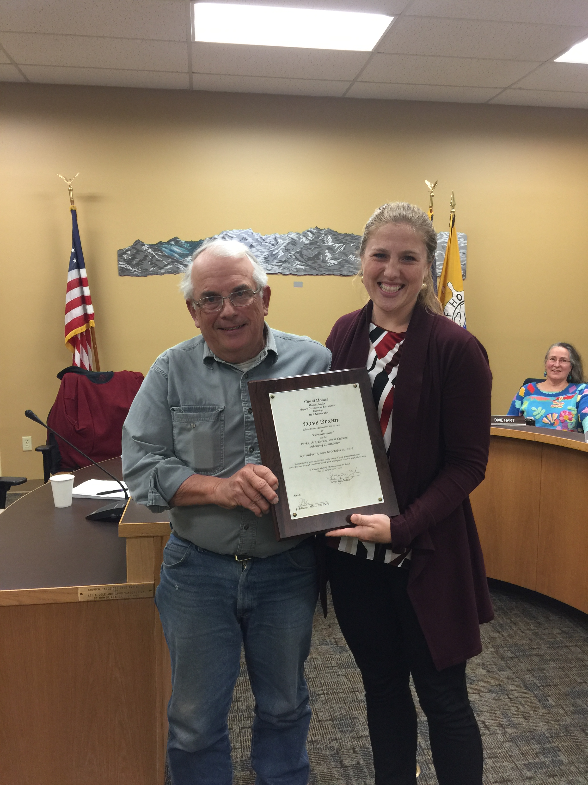 Community volunteer Dave Brann and City Manager Katie Koester pose for a photo after Koester presents Brann with a plaque thanking him for many years of service on the city's Parks, Arts, Recreation, and Culture Advisory Commission-Photo provided