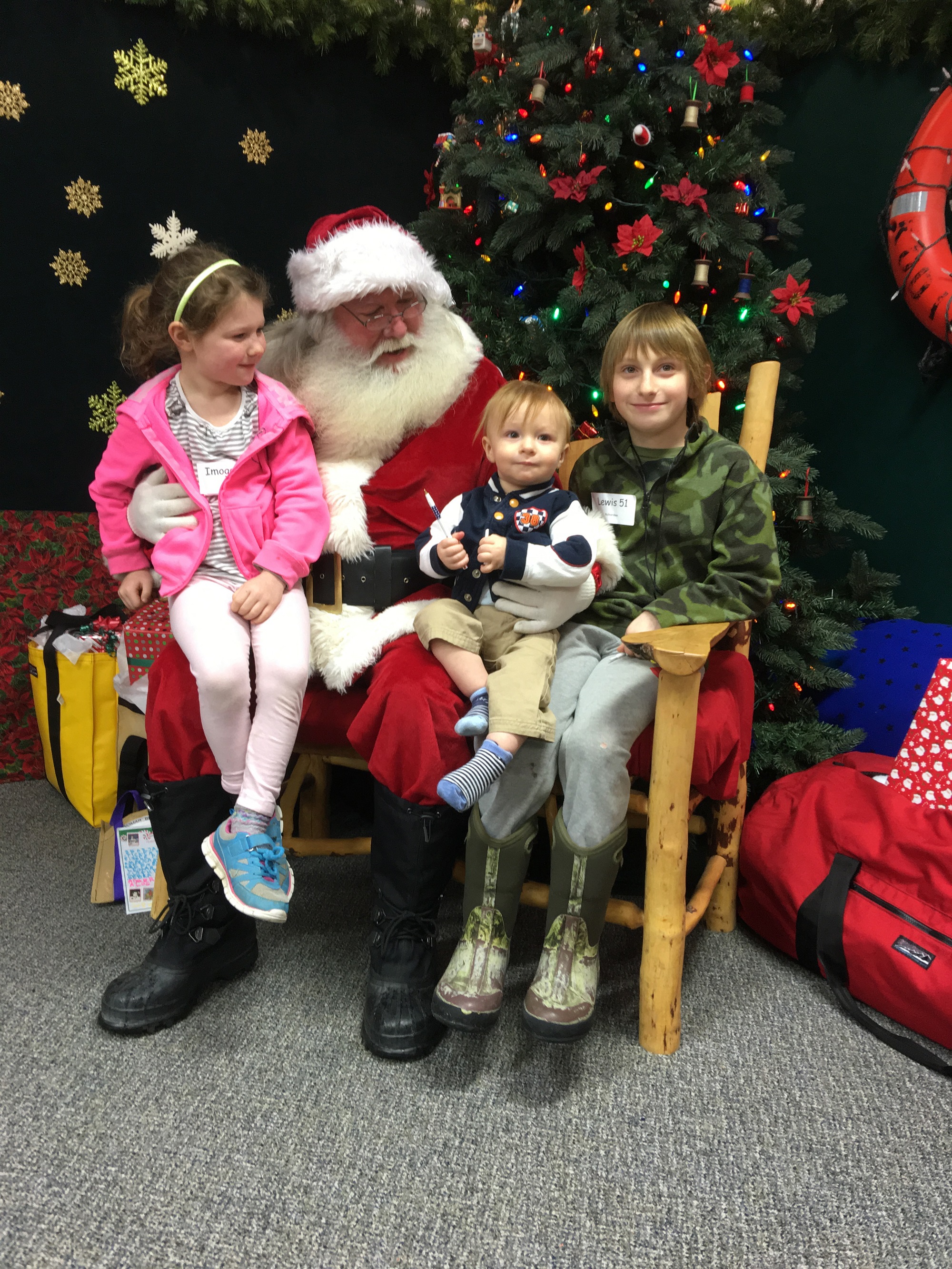 Imogen Richardson, age 7, and her brothers Erik, 1, and Lewis, 9, visit with Santa during Nomar's annual holiday open house on Sunday. Their parents are Steven and Jenna Richardson. The family is from County Mayo in Ireland and is living in Homer while Steven Richardson studies at Alaska Bible Institute.-Photo by Lori Evans, Homer News