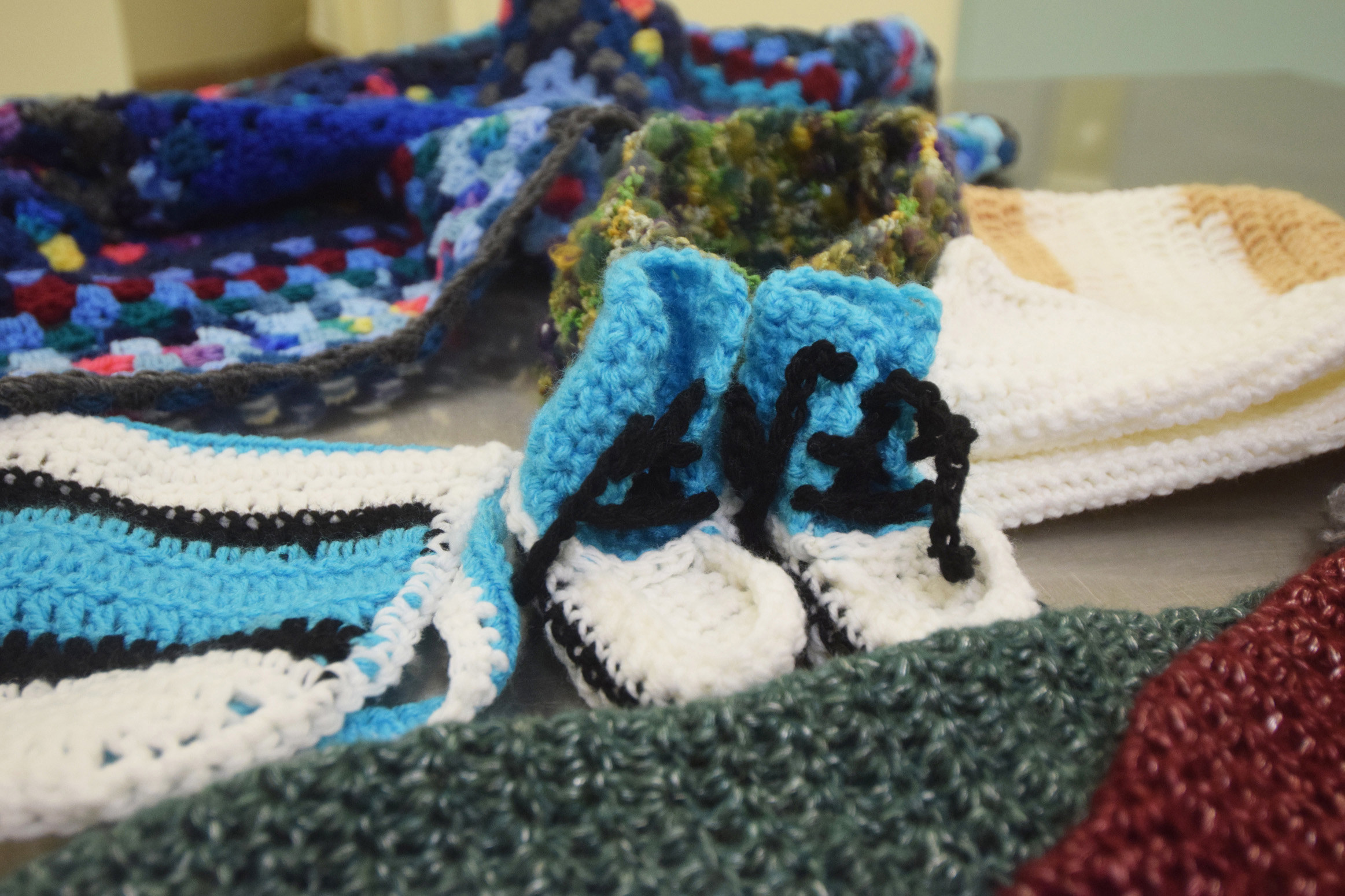 Booties, scarves, hats and more cover a table during a meeting of the Wildwood Correctional Complex's crochet program Tuesday, Nov. 29 at the complex's pretrial building in Kenai. Some of the items made by inmates are sent to Homer Thrift, where they are sold. The proceeds benefit the Child Advocacy Centers in Homer and Kenai.-Photo by Megan Pacer, Morris News Service - Alaska