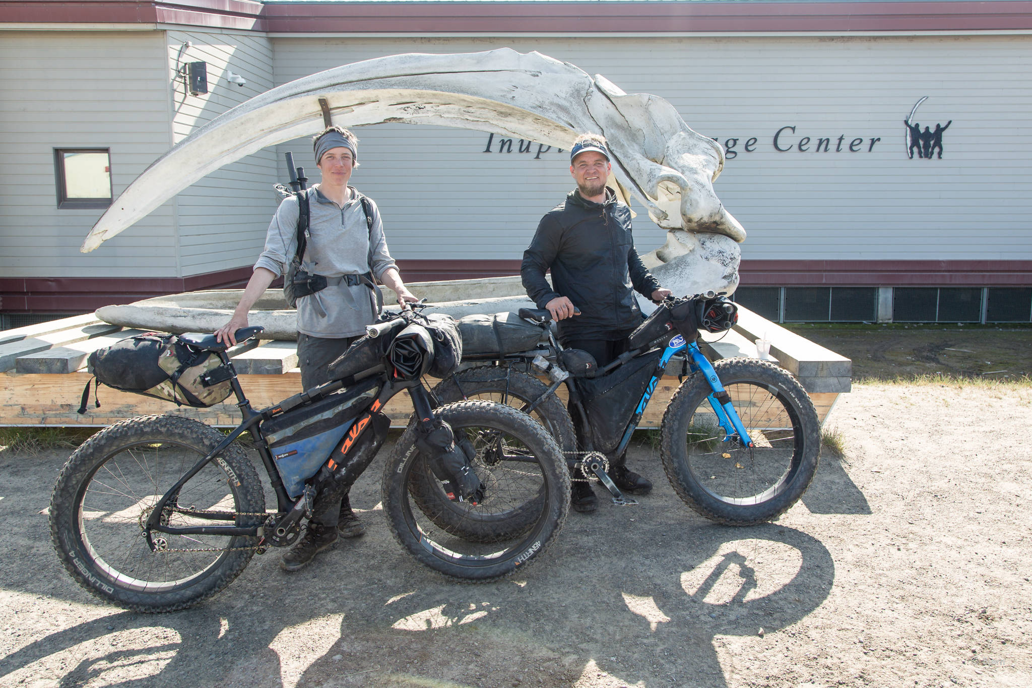 Kim McNett, left, and Bjørn Olson, right, stand with their Salsa fat bikes by a bowhead skull in Utqiagvik (formerly known as Barrow). (Photo courtesy Bjørn Olson)