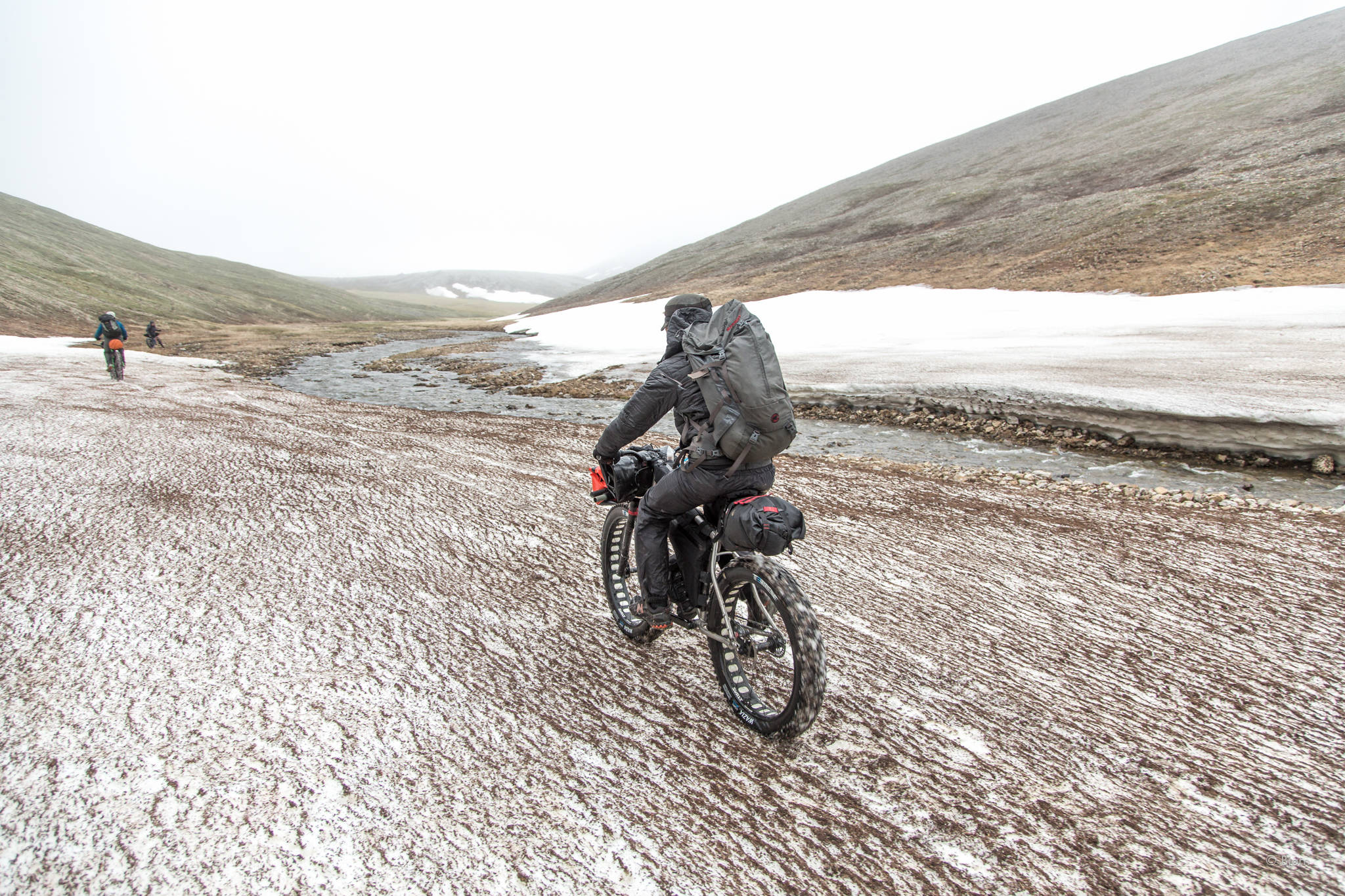 The group heads rides along snow in a creek valley. (Photo courtesy Bjørn Olson)