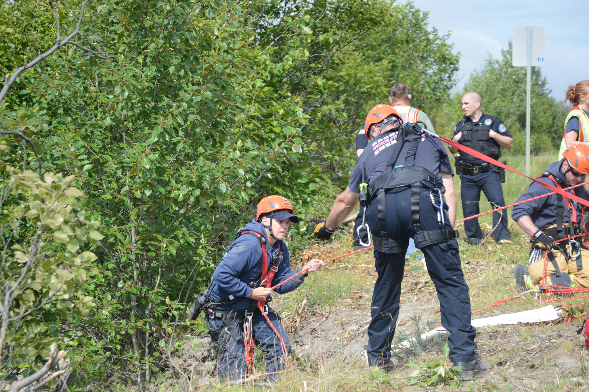 Kachemak Emergency Services assistant chief Joe Sallee helps Homer Volunteer Fire Department firefighter Tim Yarbrough climb out of a ravine about 12:30 p.m. on Monday, July 24, 2017 at the Baycrest Hill turnout in Homer, Alaska. Rescuers found a truck that had plunged over the edge, but did not find any victims. Friends of Thayr Watson, 32, later stopped by the scene to tell them Watson had crashed the truck earlier and was OK. Sallee wears a harness and tether to keep him from falling over the edge. Photo by Michael Armstrong/Homer News