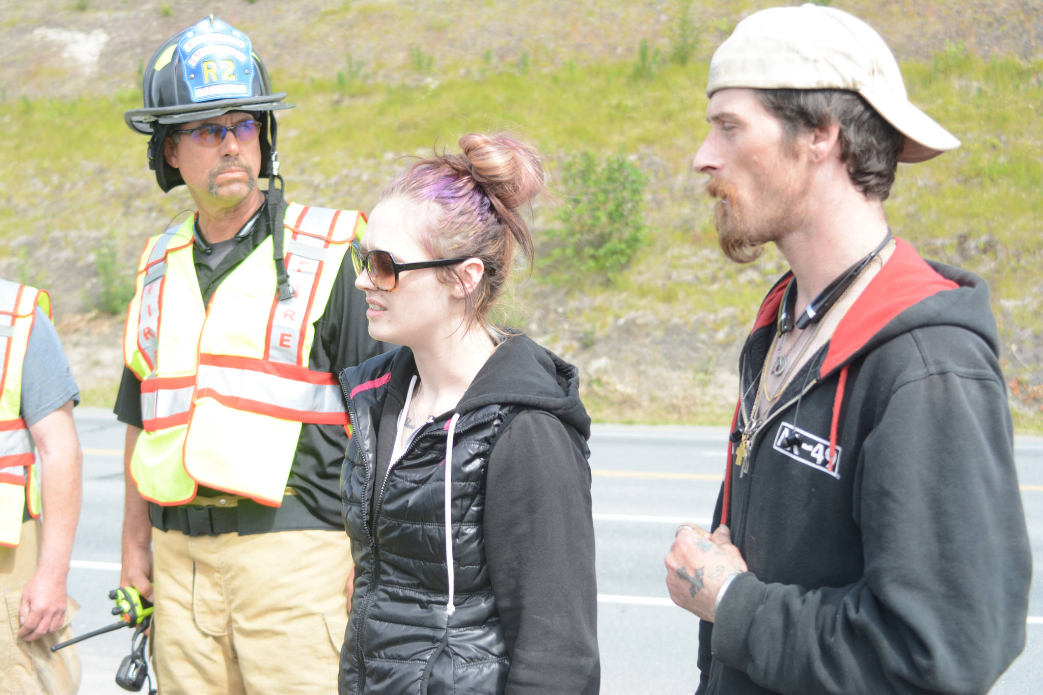 Tiffany Couch, center, tells responders that her friend, Thayr Watson, had crashed his truck into a ravine at the Baycrest Hill turnout in Homer, Alaska sometime over the weekend and climbed out on his own. Rescuers earlier on Monday, July 24, 2017 had found a truck that had plunged over the edge, but did not find any victims. They had searched about three hours on Monday before learning that Watson had walked away from the scene. Police later contacted Watson and found he was OK. Kachemak Emergency Services firefighter Greg Collins, left, watches. At right is Watson’s friend, Tim Taylor. Photo by Michael Armstrong/Homer News
