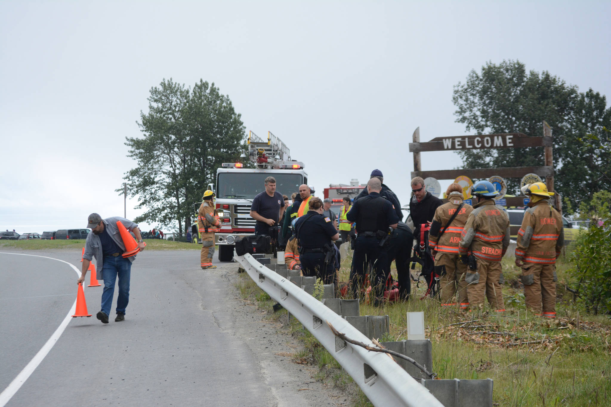 Kachemak Emergency Services volunteer firefighter Jason Miller, left, about noon on Monday, July 24, 2017 sets out traffic cones at the Baycrest Hill turnout as rescuers prepare to rope up to climb down and inspect a truck crash in Homer, Alaska. Photo by Michael Armstrong/Homer News
