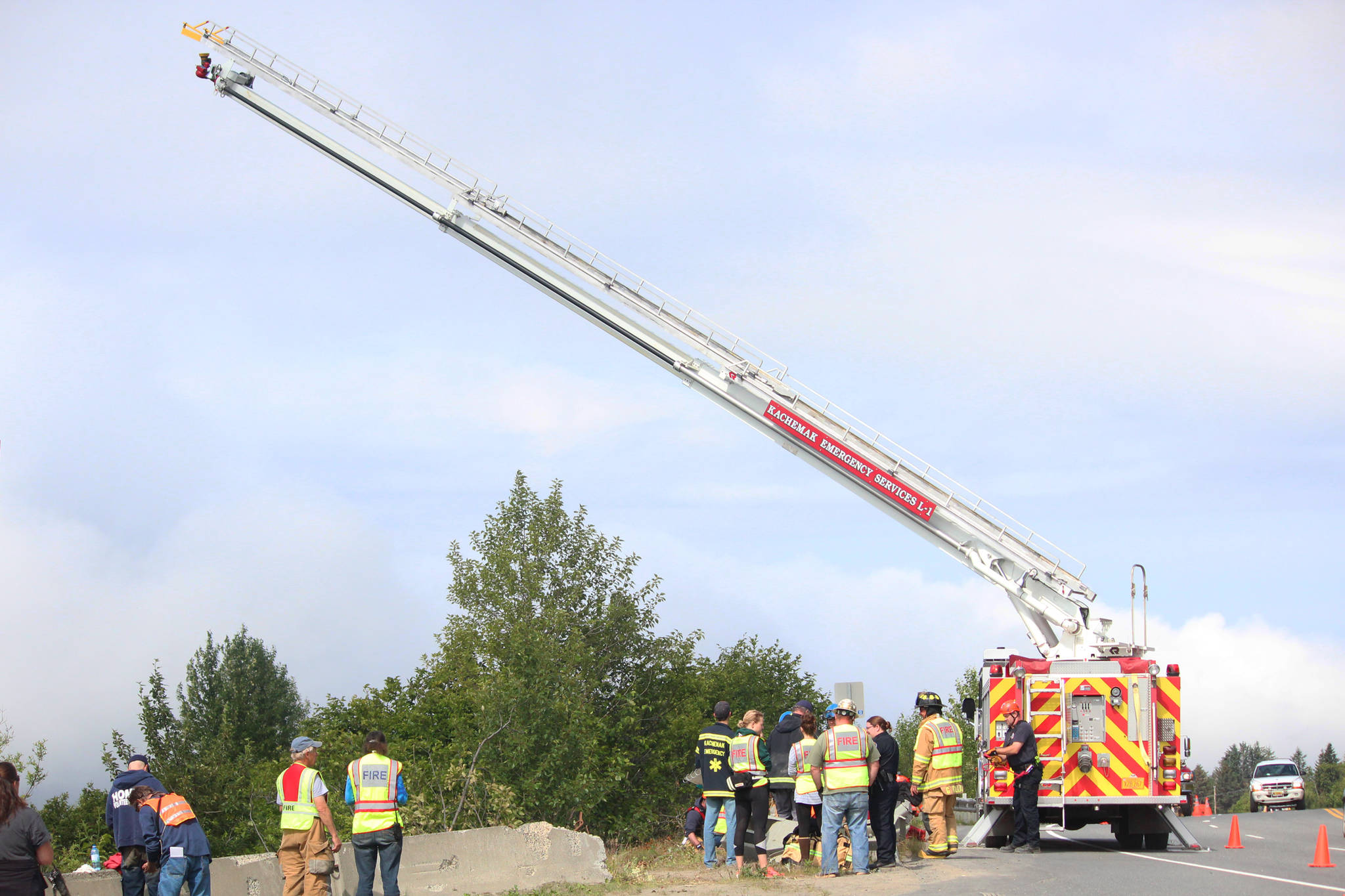 First responders wait while a ladder truck is set up to allow firefighters to climb up and get a better view of the slope near Baycrest Overlook on Monday, July 24, 2017 in Homer, Alaska. First responders found a pickup truck that had fallen over the edge after hitting a guardrail, and searched for a possible victim until getting a report that the driver had crashed several days earlier and had walked away uninjured. Photo by Megan Pacer/Homer News