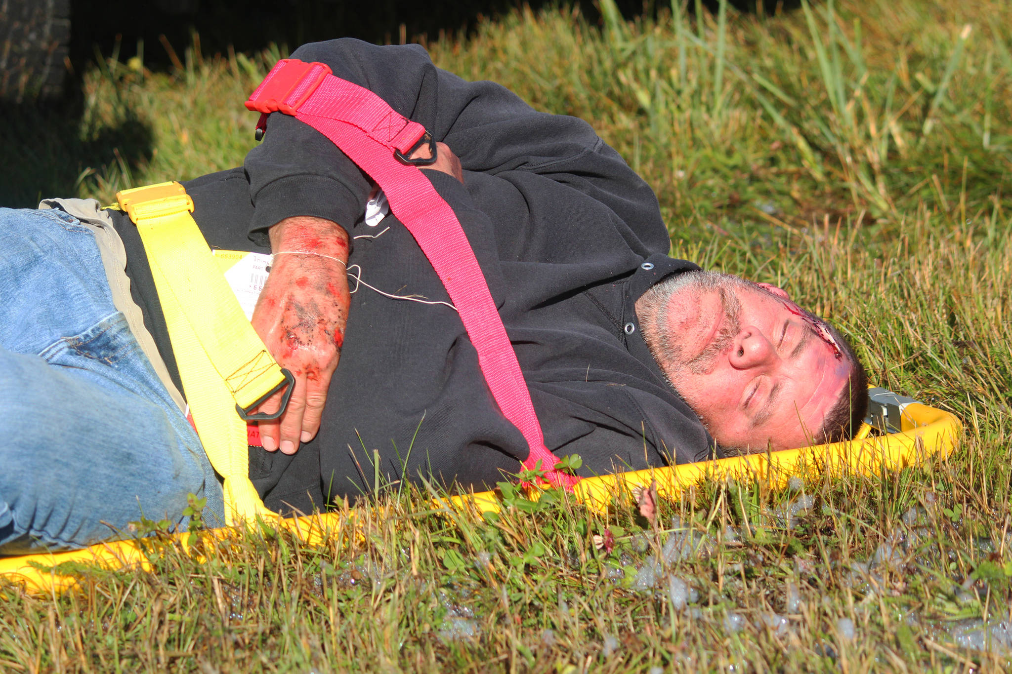 John Dunson, an equipment operator and firefighter for the Homer Airport, poses as an injured plane crash victim during an emergency exercise Saturday, Aug. 19, 2017 at the airport in Homer, Alaska. Dunson and more than 20 community members volunteered to participate as crash victims for the drill that’s required every three years for the airport to remain in Federal Aviation Administration compliance. (Photo by Megan Pacer/Homer News)