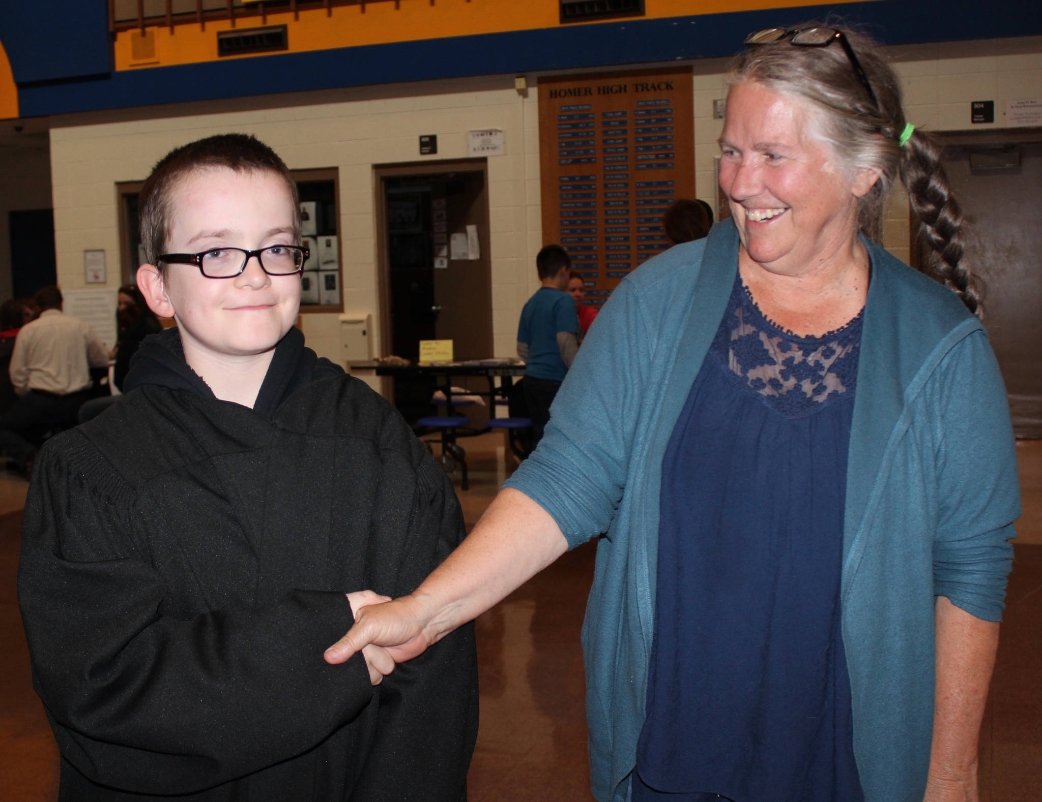 Here comes the judge! At the Aug. 16 Youth After School Activities and Programs event sponsored by K-Bay Community Youth and Activities Coalition, Ethan Lurus, decked out in a judge’s robe, shakes hands with Ginny Espinshade, Kenai Peninsula Youth Court executive director. (Photo by McKibben Jackinsky, for the Homer News)