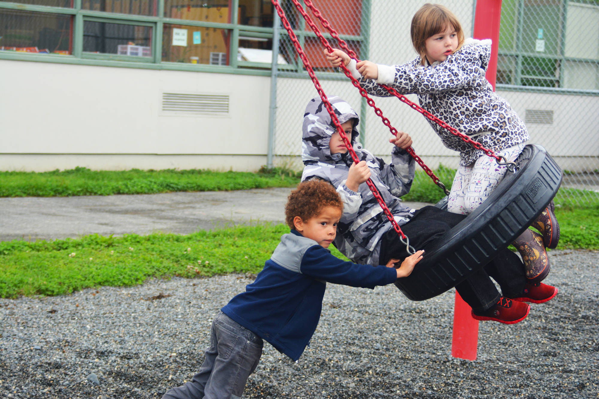 Elijah Williams pushes Adrian Reutov and Autumn Read on a swing during recess on the first day of school Tuesday, Aug. 22, 2017 at Paul Banks Elementary in Homer, Alaska. (Photo by Megan Pacer/Homer News)