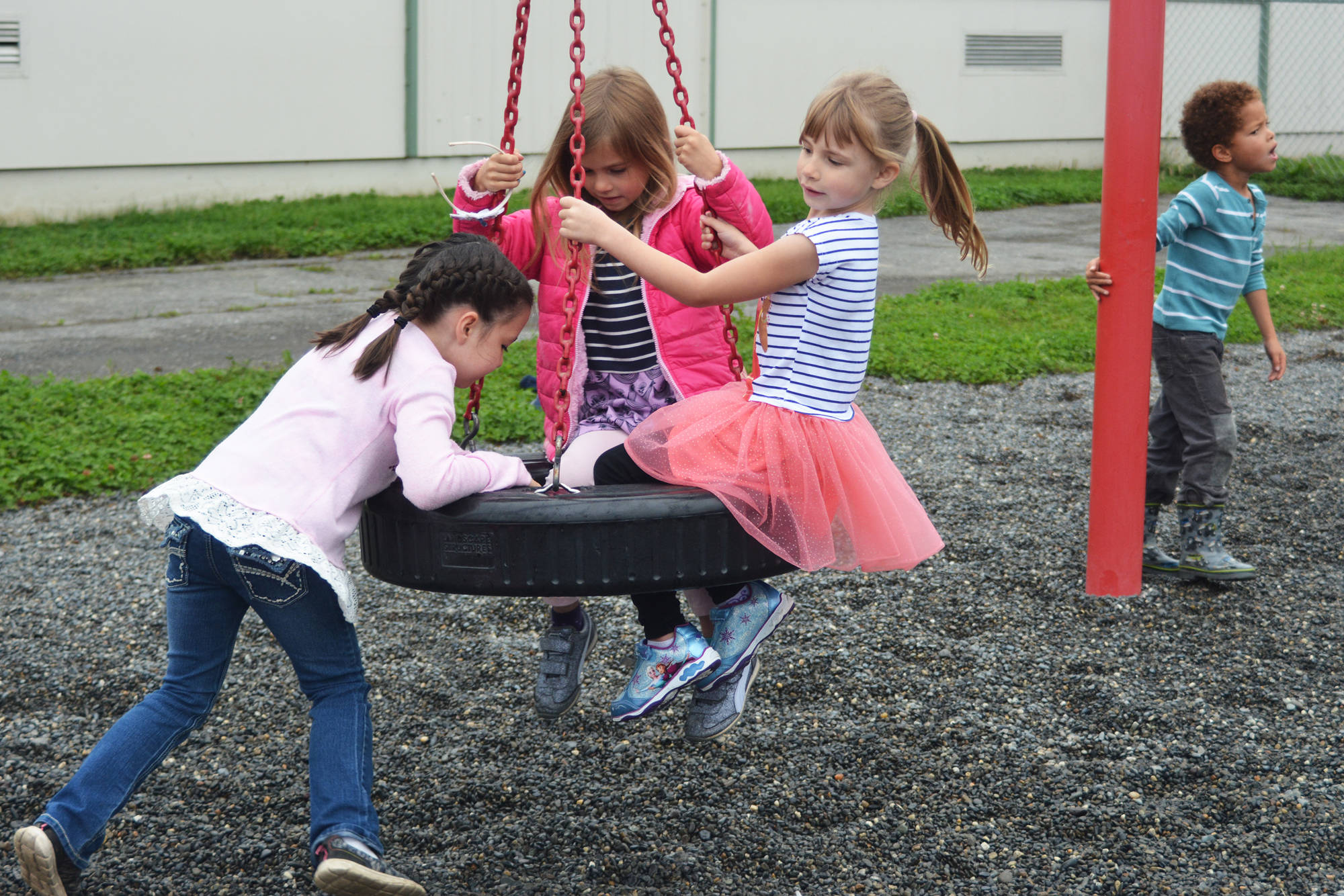 Sydney Abell pushes Jillian Koran (center) and Grace Shover (right) on a swing during recess on the first day of the school year Tuesday, Aug. 22, 2017 at Paul Banks Elementary in Homer, Alaska. (Photo by Megan Pacer/Homer News)
