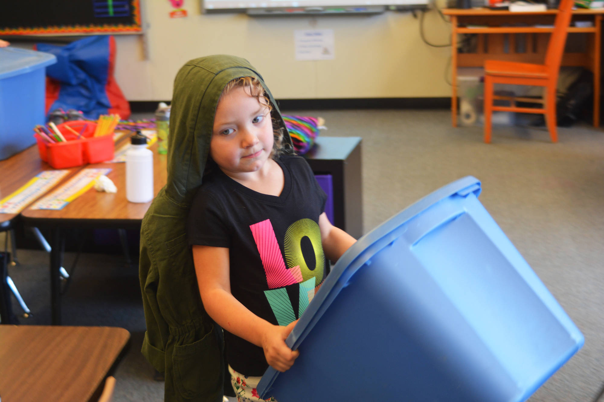 Olivia Pitzman, a kindergartener, carries her tub of outside clothes to a desk as she prepares to head outdoors for recess on the first day of the school year Tuesday, Aug. 22, 2017 at Paul Banks Elementary in Homer, Alaska. (Photo by Megan Pacer/Homer News)