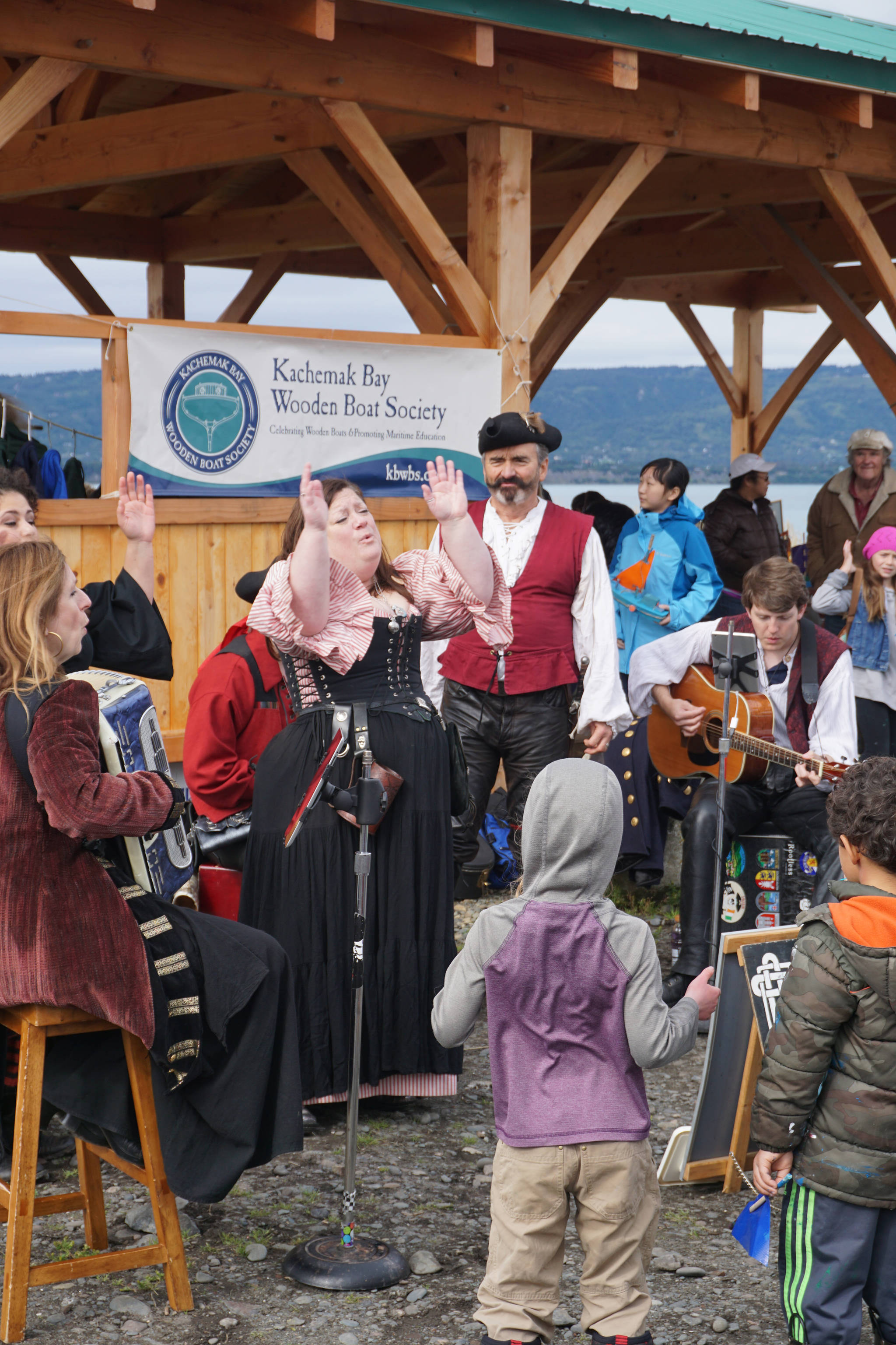 Erin Searcy-Dudgeon Wells of Rogues & Wenches, center, leads a sing along at the Kachemak Bay Wooden Boat Society Festival on Saturday, Sept. 2, 2017 at the Nick Dudiak Fishing Lagoon campground in Homer, Alaska. At left are Lucia Woofter and Lena Gonzales. At far right is Hunter Woofter, Devin Frey, second from right, and Bob Woofter, (Photo by Michael Armstrong, Homer News)