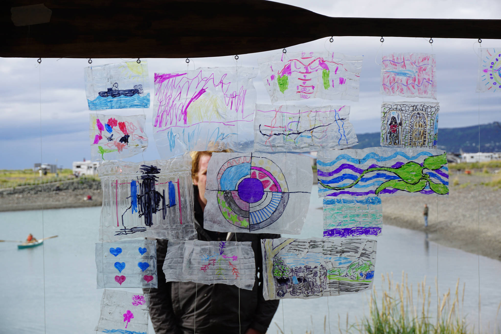 Henry Rieske of the Center for Alaskan Coastal Studies stands behind a mosaic at the Kachemak Bay Wooden Boat Society Festival on Saturday, Sept. 2, 2017 at the Nick Dudiak Fishing Lagoon campground in Homer, Alaska. Artists were invited to draw on pieces of water bottles found on Augustine Island during a marine debris clean up. (Photo by Michael Armstrong, Homer News)