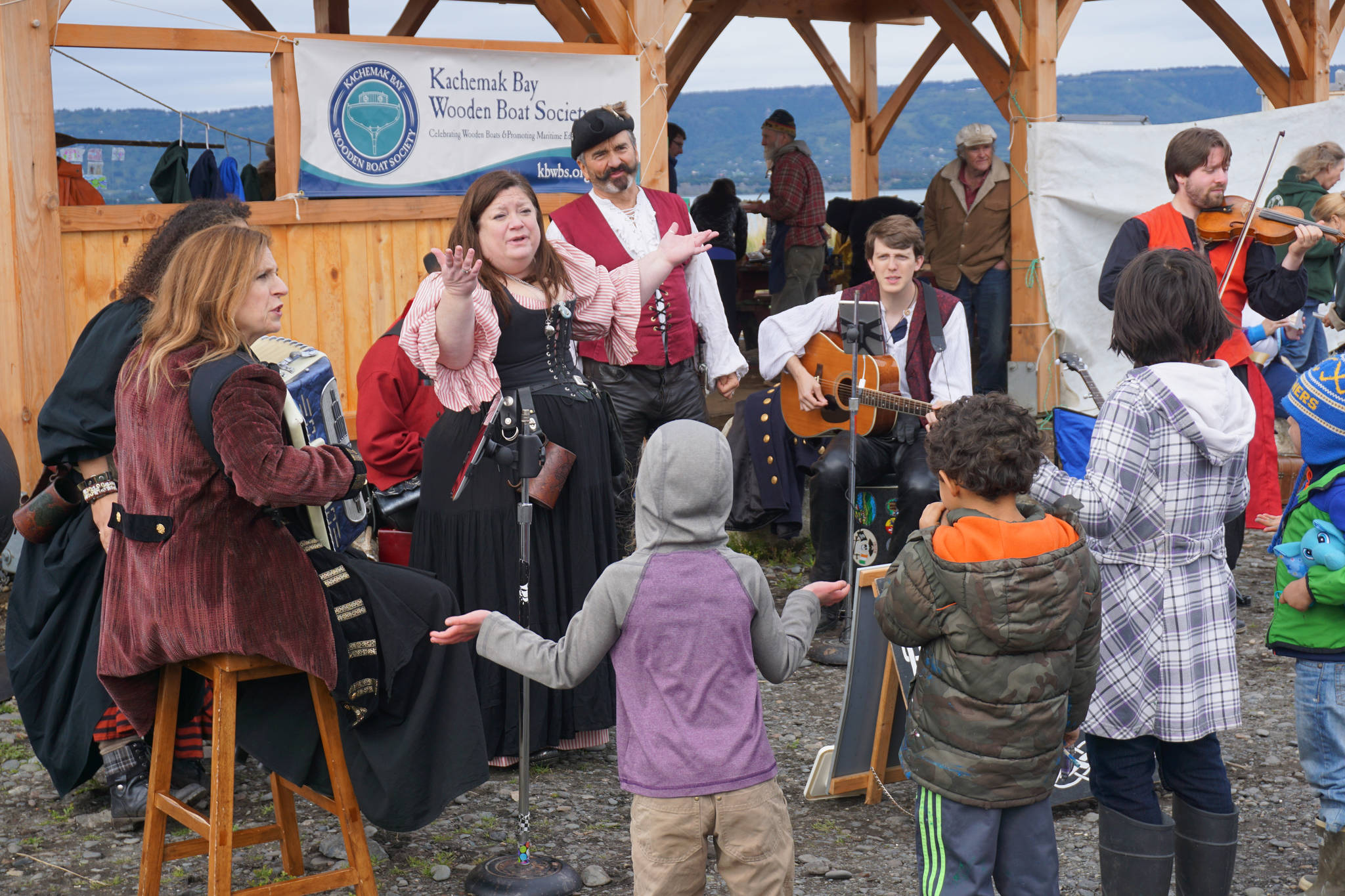 Erin Searcy-Dudgeon Wells of Rogues & Wenches, center, leads a sing along at the Kachemak Bay Wooden Boat Society Festival on Saturday, Sept. 2, 2017 at the Nick Dudiak Fishing Lagoon campground in Homer, Alaska. At left are Lucia Woofter and Lena Gonzales. At far right is Hunter Woofter, Devin Frey, second from right, and Bob Woofter. (Photo by Michael Armstrong, Homer News)