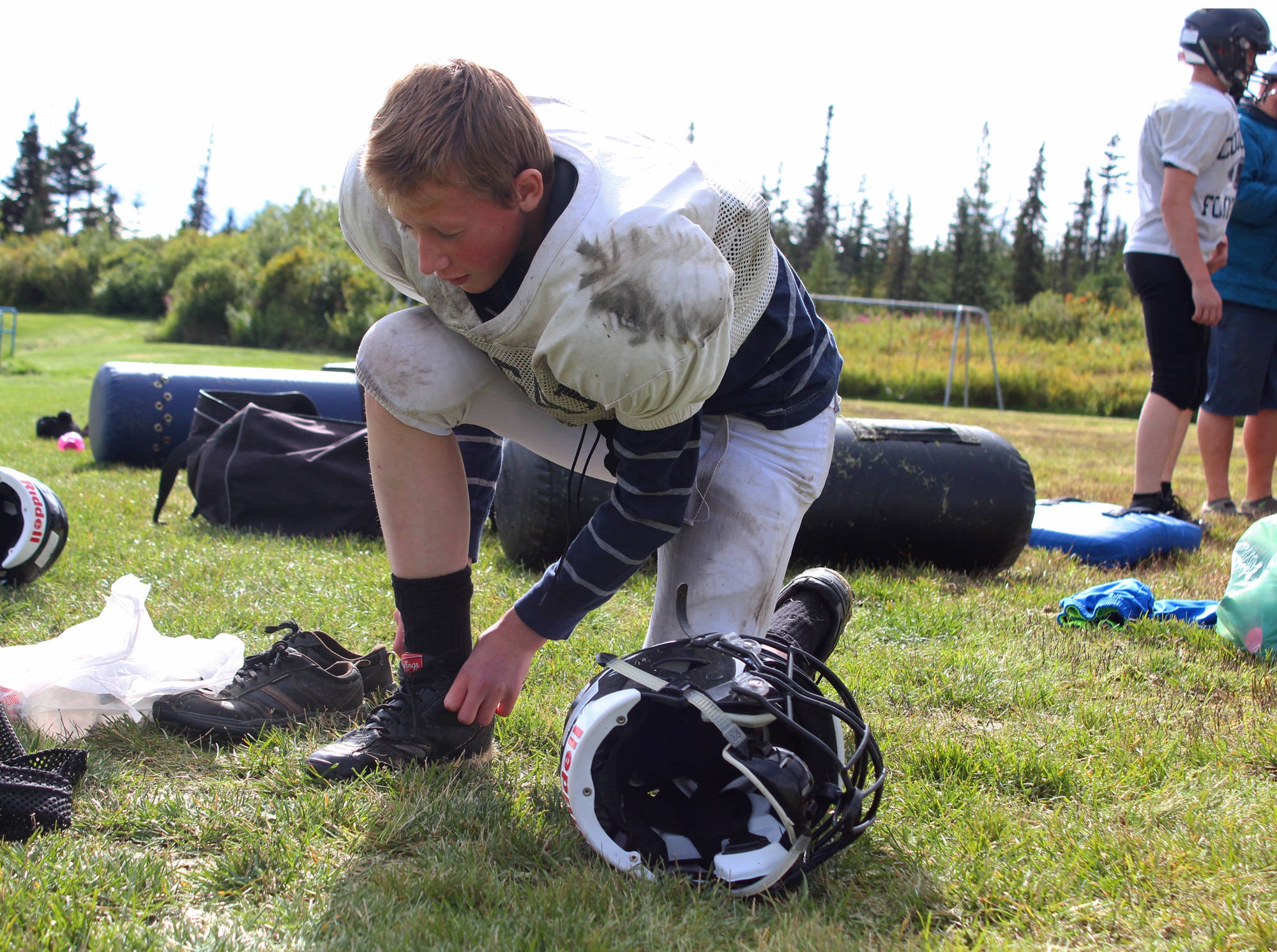 Foma Reutov, a freshman, ties up his shoes before a Cougars football practice Friday, Sept. 1, 2017 at McNeil Canyon Elementary in Fritz Creek, Alaska. The team, usually made up of a mix of students from the Russian Old Believer Villages Voznesenka, Razdolna and Kachemak-Selo, is in its fifth year as a varsity, 11-man program. (Photo by Megan Pacer/Homer News)