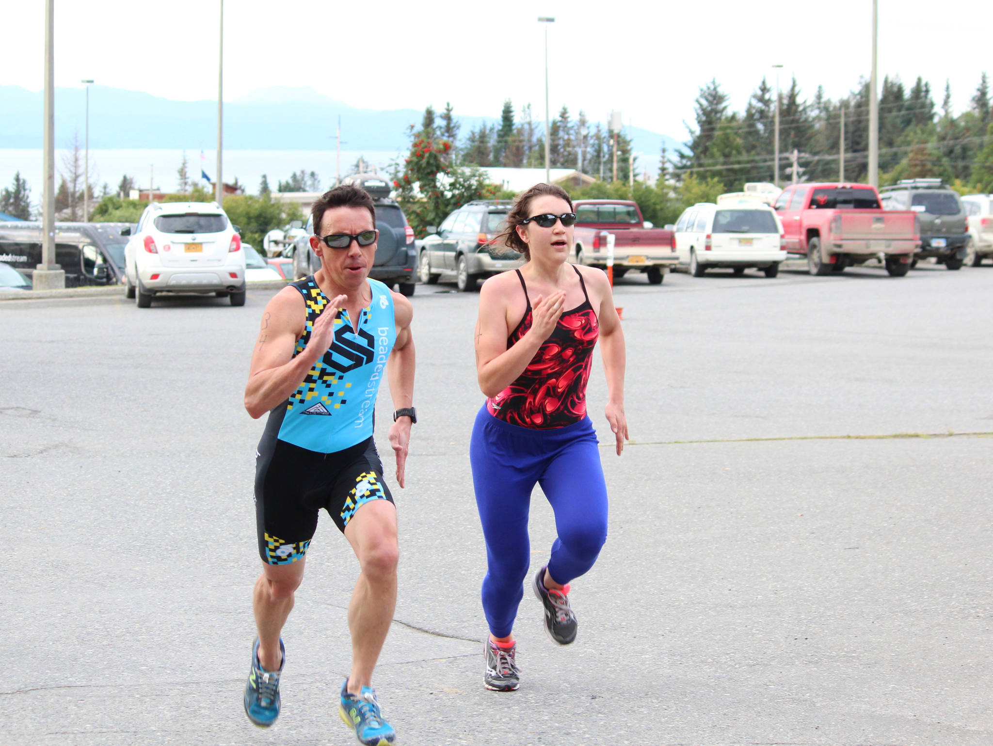 Anchorage resident Brian Shumaker and Kristin Faulkner, who used to swim for Homer High School before she went to college and then moved to New York, race each other to the finish line of the Homer Mariner Triathlon at Homer High School on Saturday, Sept. 2, 2017 in Homer, Alaska. The two remained on each other’s tail throughout much of the race before Shumaker passed Faulkner at the last second to claim first overall. (Photo by Megan Pacer/Homer News)