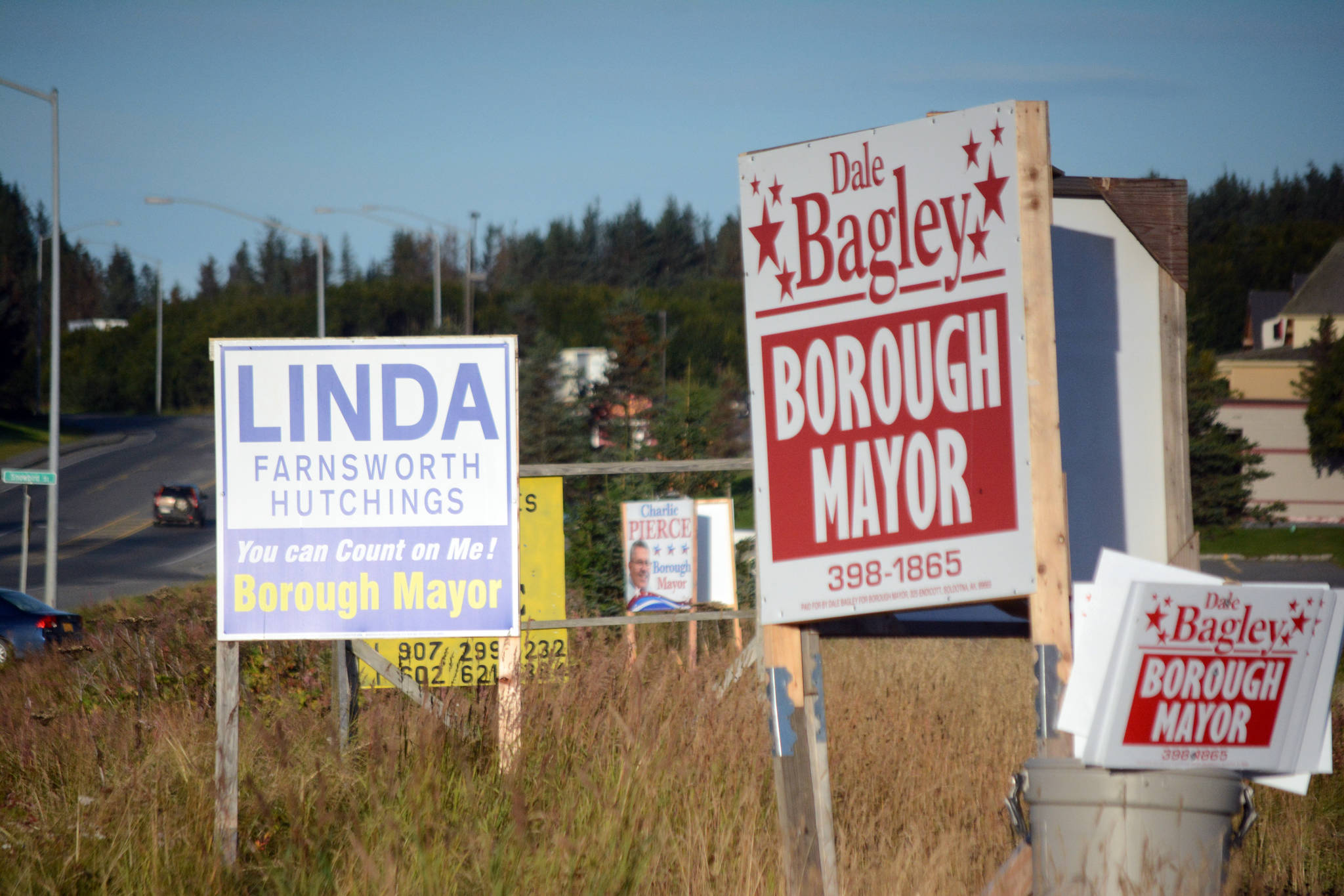 Campaign signs for Kenai Peninsula Borough mayoral candidates, shown here Monday, Sept. 11, 2017, have been placed on a lot along the Homer Bypass at the corner of Lake Street. According to state law, no sign visible and legible from the road can be placed along state right of ways such as the Bypass and Lake Street unless the sign is related to a business. The “for sale” sign the background would be legal. (Photo by Michael Armstrong/Homer News)